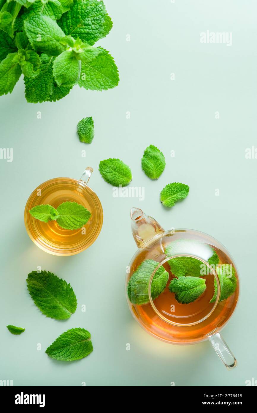 Tasse Tee und Teekannen mit Minzblättern auf grünem Hintergrund. Flach liegend, Draufsicht. Stockfoto