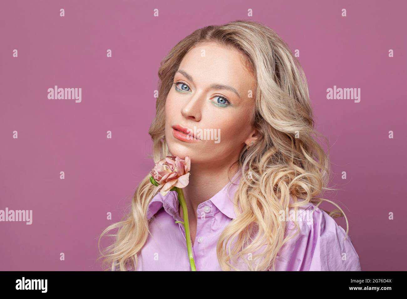 Blonde Frau reifes Modell mit rosa Blume auf rosa Banner Hintergrund Stockfoto