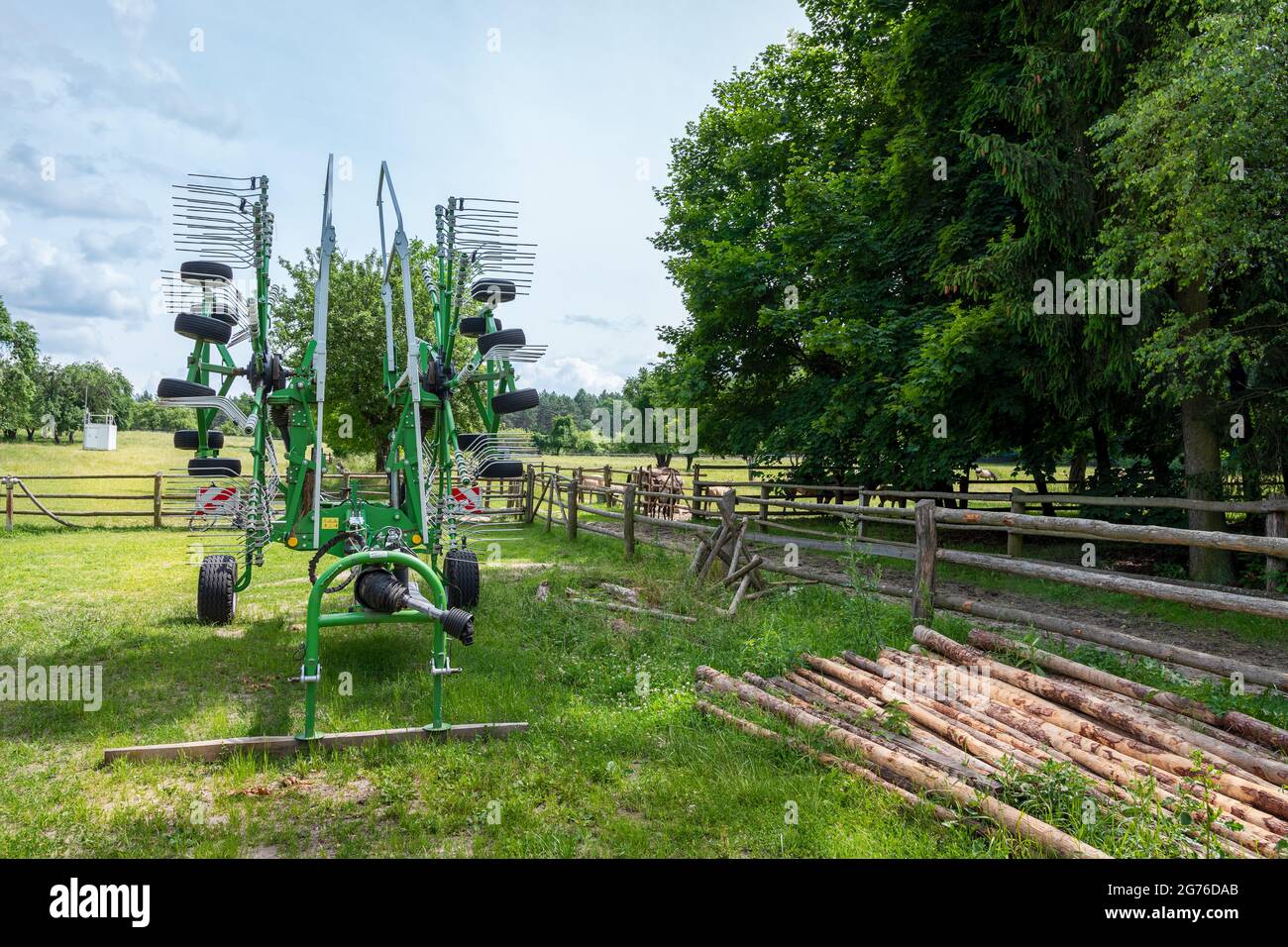 Bunte Landmaschinen - ländliche Geräte stehen auf einem Bauernhof, umgeben von Bäumen an einem sonnigen Tag Stockfoto