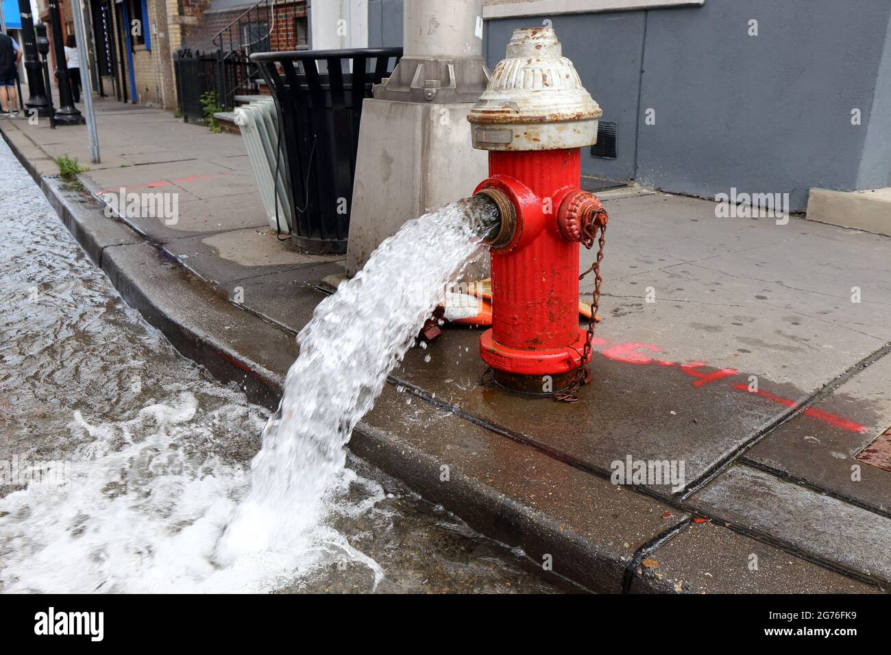 Ein offener Hydrant, der Wasser in die Straße sprudelt. Stockfoto