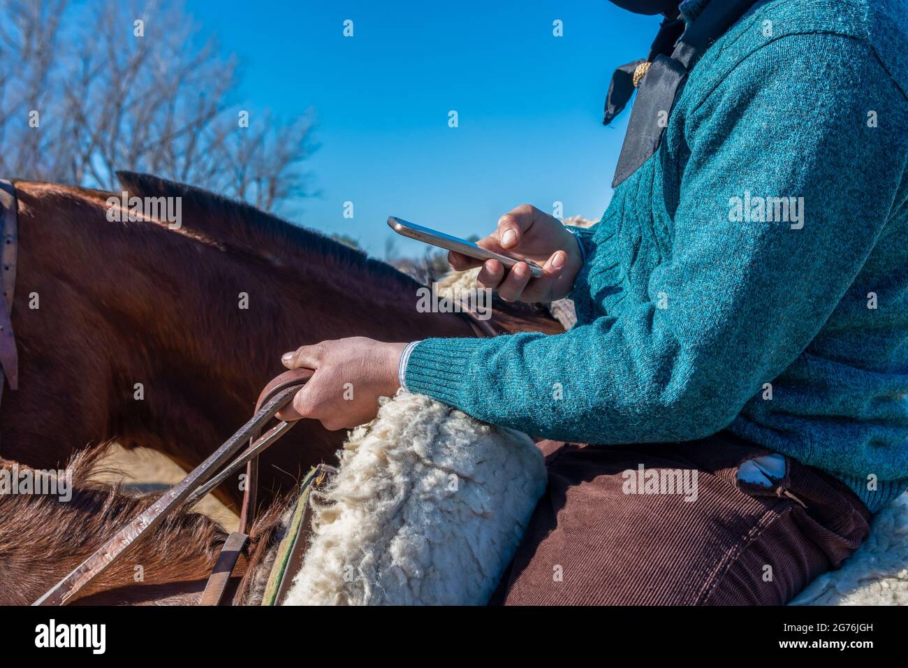 Ein argentinischer Gaucho auf dem Pferderücken, mit einem Handy Stockfoto