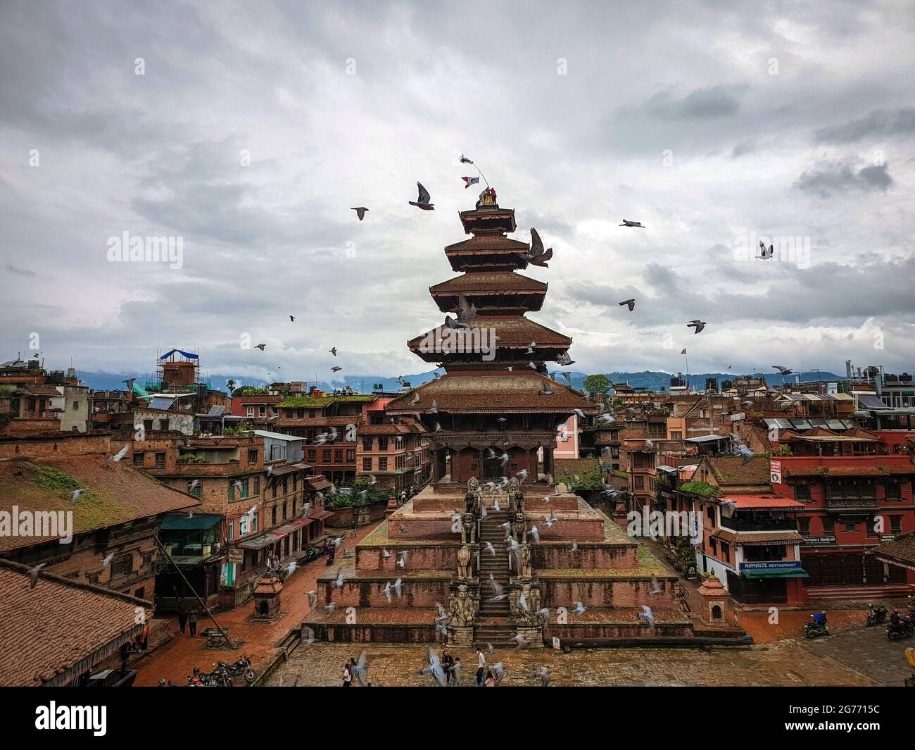 Bhaktapur, Bagmati, Nepal. Juli 2021. Tauben fliegen, während Menschen aus der Gemeinde Newar während eines Kulturrituals namens „Bushwara“ (Platzierung der Flagge), anlässlich des 320. Jahrestages der Gründung, eine Flagge auf der Spitze des Nyatapola-Tempels platzieren. Der fünfstöckige Nyatapola-Tempel, der 1702 n. Chr. erbaut wurde, ist eine ikonische Architektur, das Wahrzeichen der Nation und auch für das Symbol des Friedens, des Wohlstands und der Einheit bekannt. Quelle: Sunil Sharma/ZUMA Wire/Alamy Live News Stockfoto