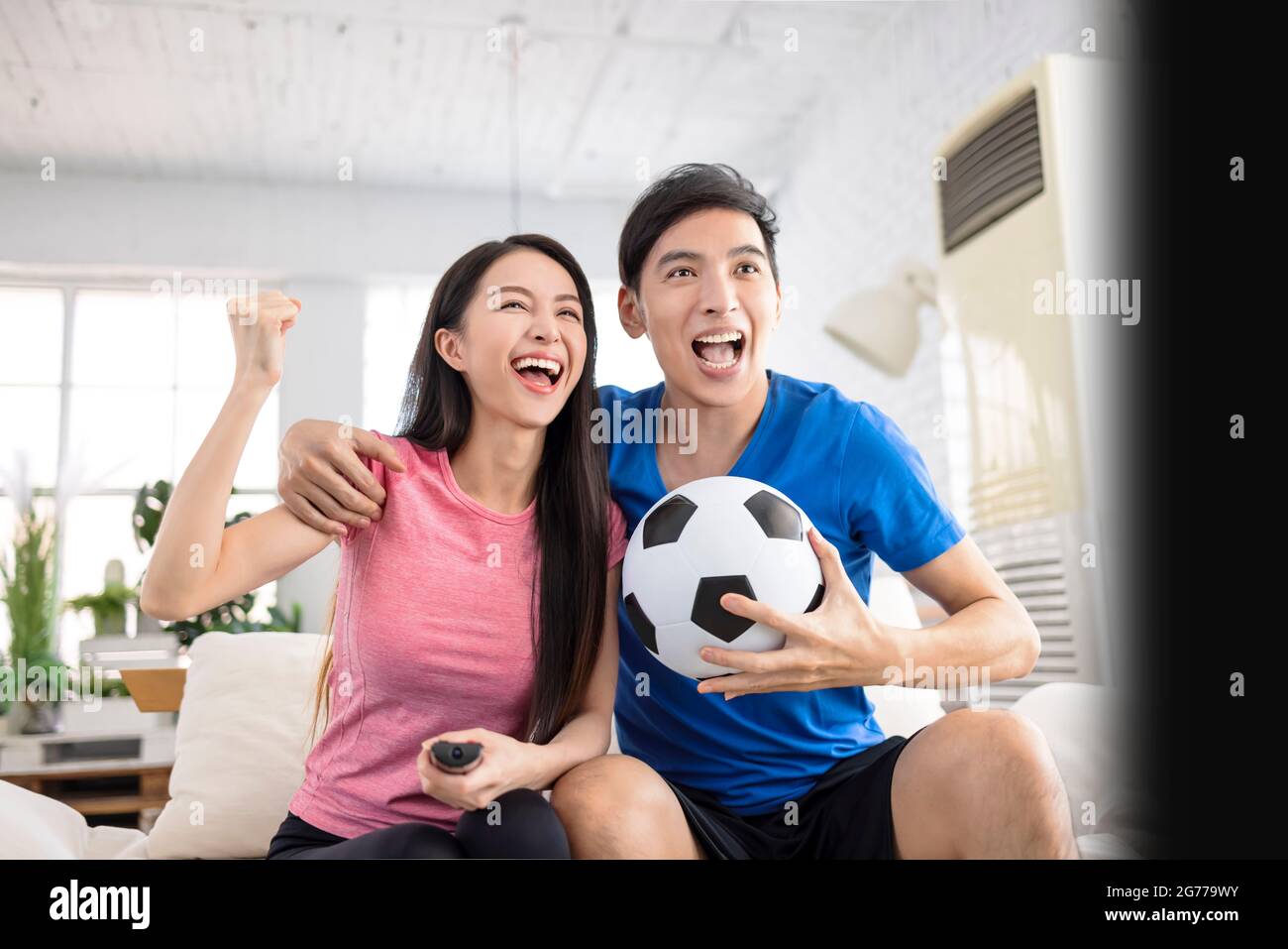 Aufgeregt Junges Paar Fernsehen und die Hände heben, um den Sieg zu feiern Stockfoto