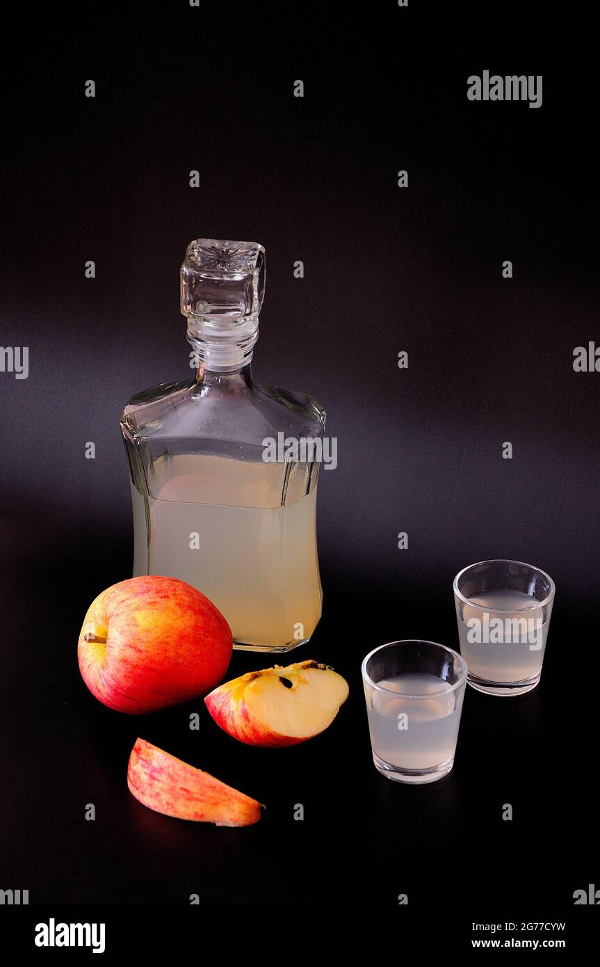 Apfel Calvados in einer Flasche und zwei Gläsern, reife Früchte in Stücke  geschnitten neben einem schwarzen Hintergrund. Nahaufnahme Stockfotografie  - Alamy