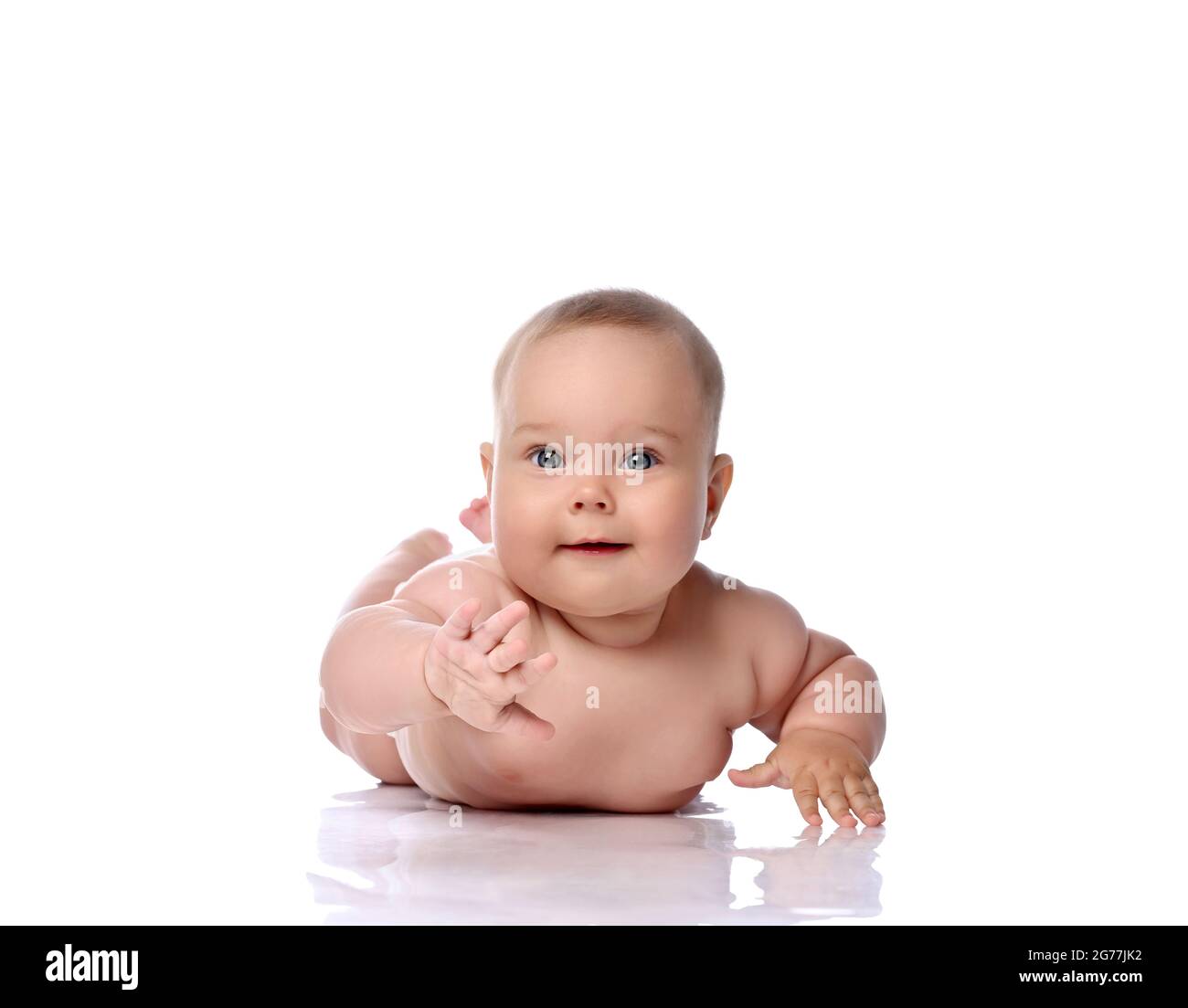 Glücklich neugierig Kleinkind Baby Mädchen Kind in Windel liegt auf ihrem Bauch, Magen versucht zu erreichen, berühren Kamera Stockfoto