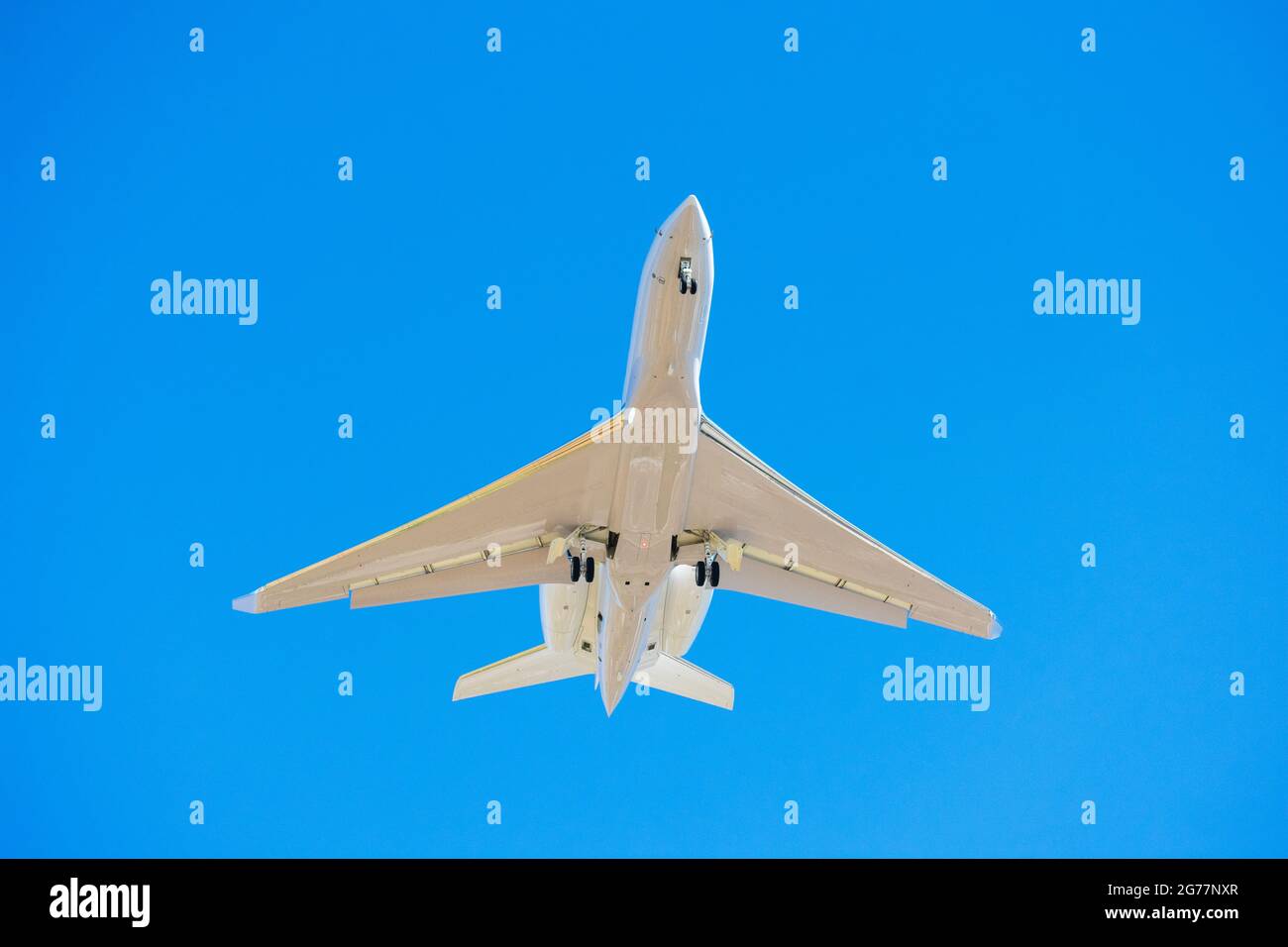 Kleiner Business Jet mit Landescheinwerfer und eingesetztem Fahrwerk zur Vorbereitung auf die Landung am Flughafen. Blauer Himmel Stockfoto