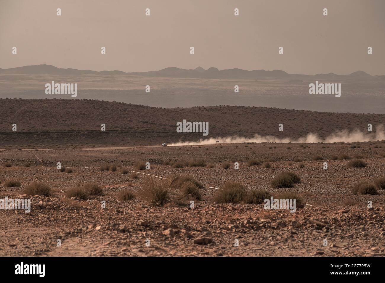 Entferntes Auto, das durch Wüste Schotterstraße mit Staubwolken Spur in Namibia bewegt Stockfoto