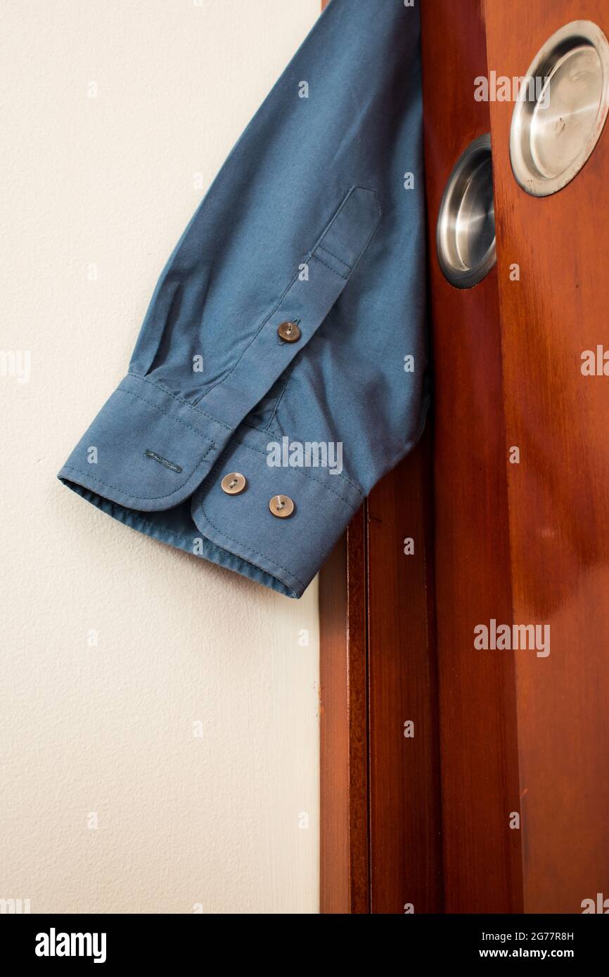 Vertikale Aufnahme eines Hemdblemens, der zwischen der Schranktür in einem Raum eingeklemmt ist Stockfoto