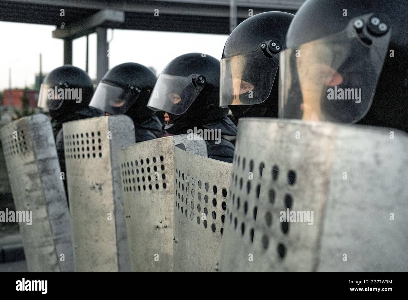 Eine Gruppe von Polizeikräften in Bereitschaftskleidung, die in Reihe stehen und Schilde halten, während sie sich vor Unruhen schützen Stockfoto