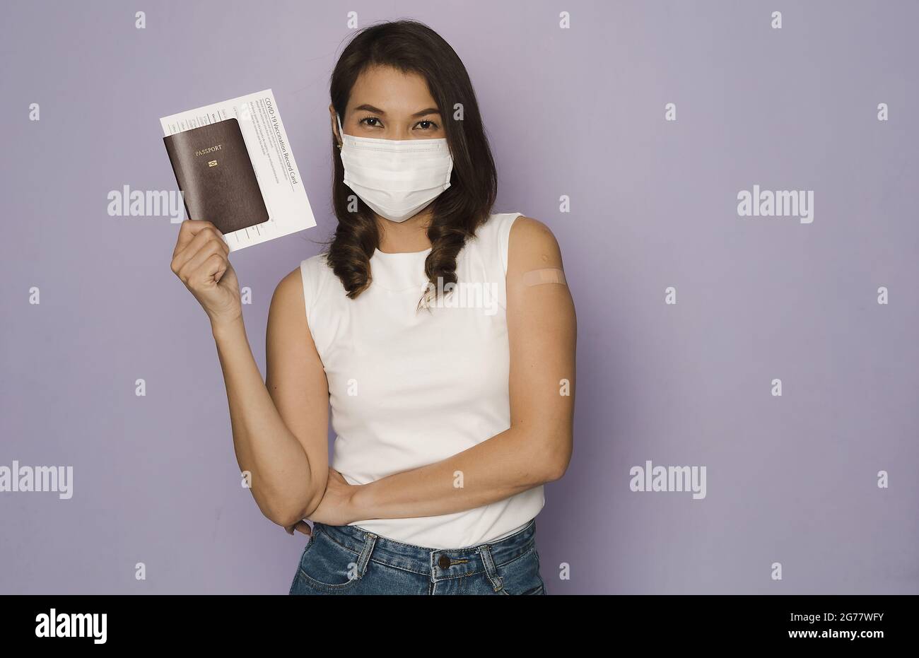 Frau trägt schützende Hygiene Gesichtsmaske mit Pass und Impfkarte zeigen, um die Kamera. Konzept für neue Normalreisende zertifiziert Stockfoto