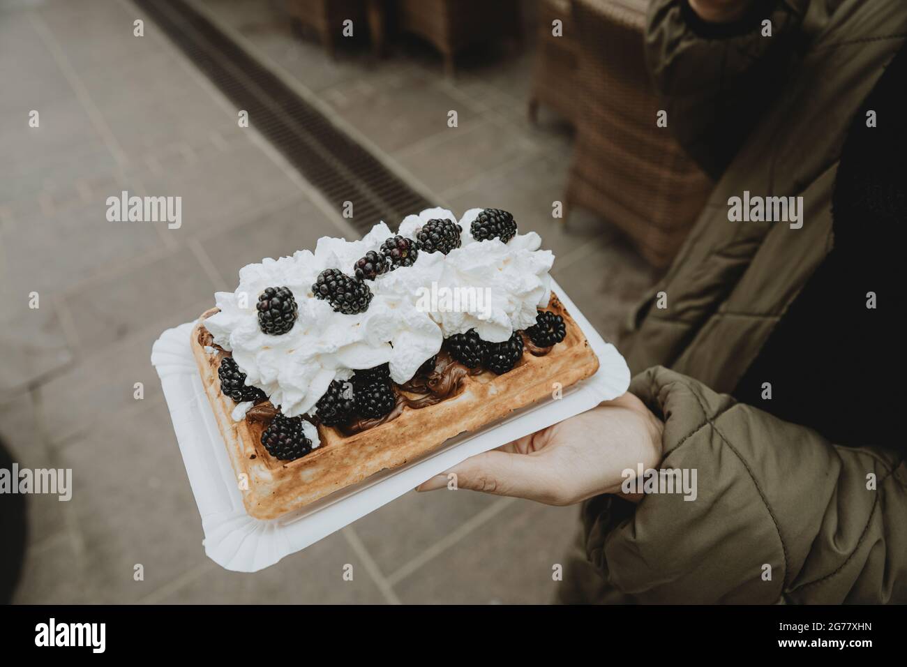 Detail der traditionellen polnischen Spezialität Gofry mit Schlagsahne und Brombeeren auf Frauenhand Stockfoto
