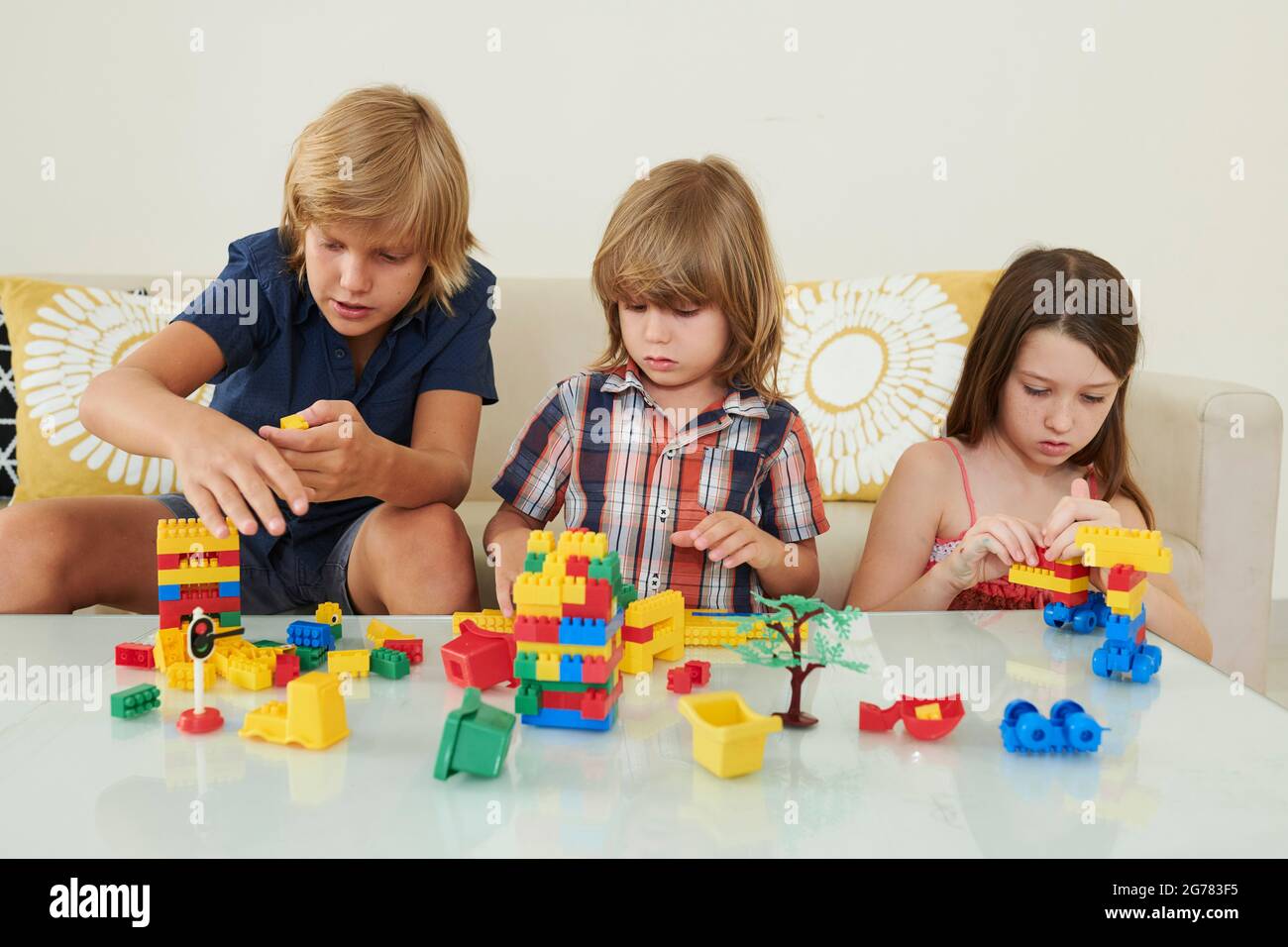 Kinder spielen mit bunten Spielzeugsteinen zusammen am Tisch im hellen Spielzimmer Stockfoto