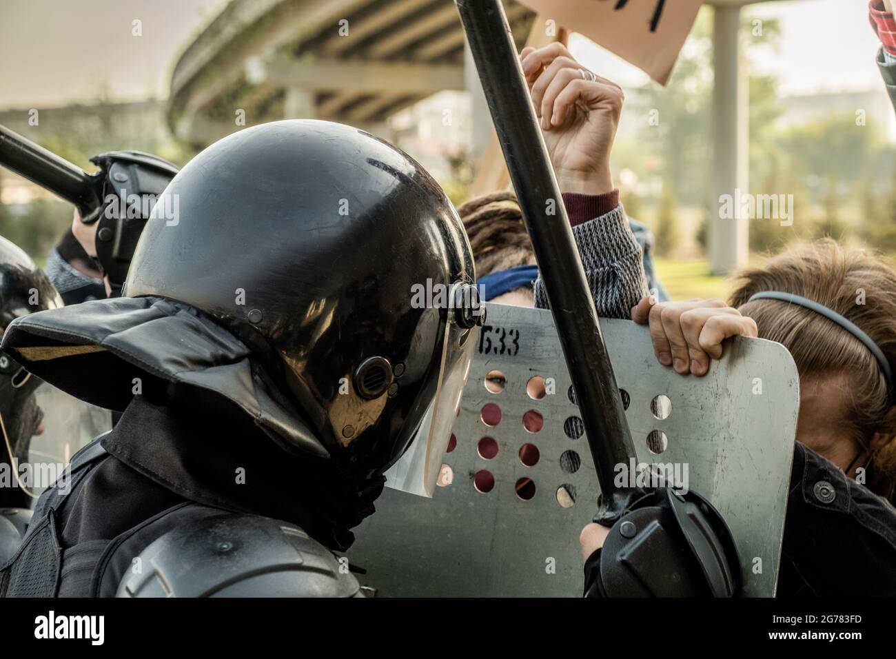 Die Polizei ist in Helmen mit Schilden und Schlagstöcken unterwegs und schiebt eine Menge von Demonstranten, während sie sie auf der Straße hält Stockfoto