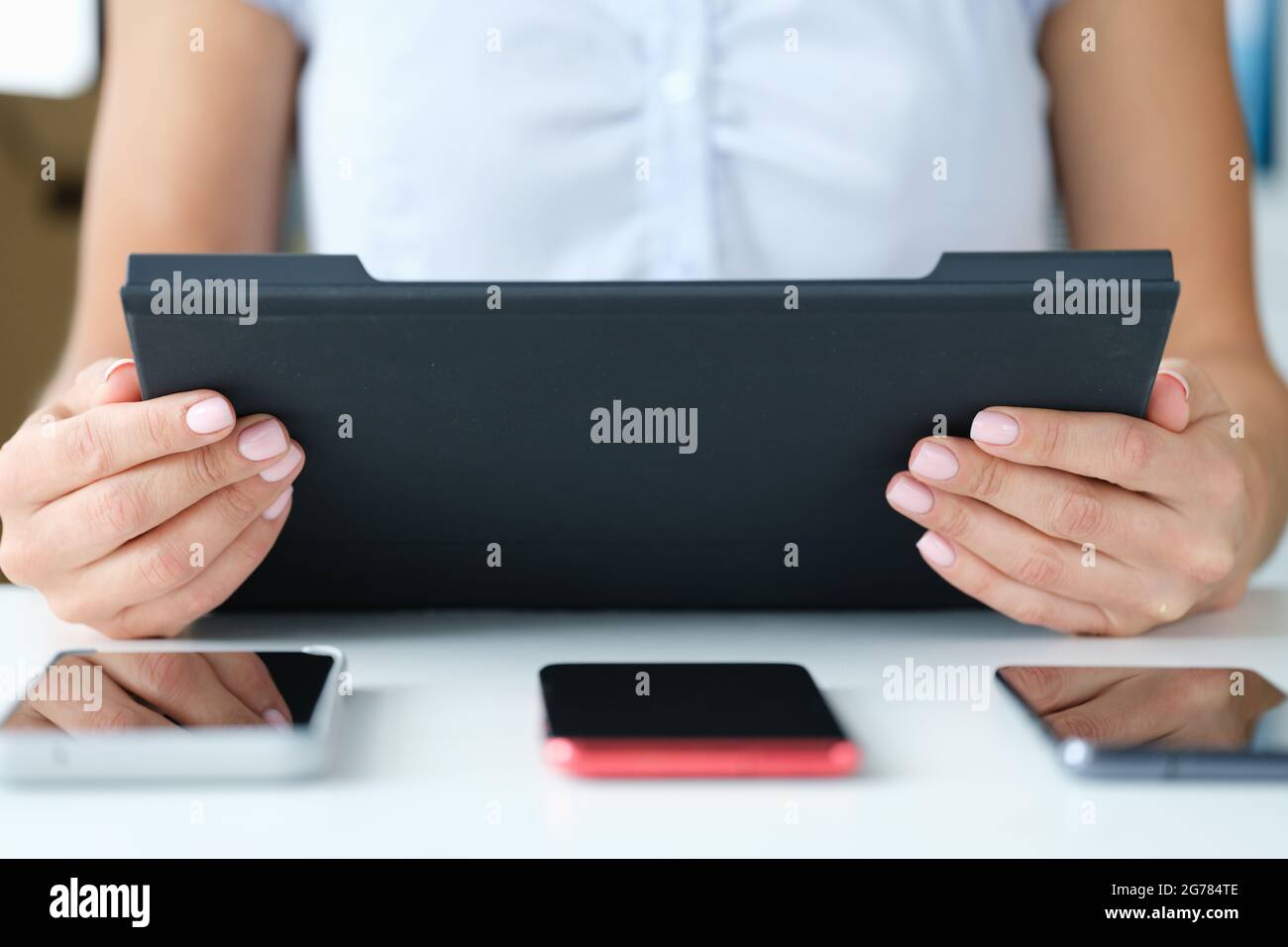 Frau hält Tablet auf dem Tisch drei Smartphones lügen Stockfoto
