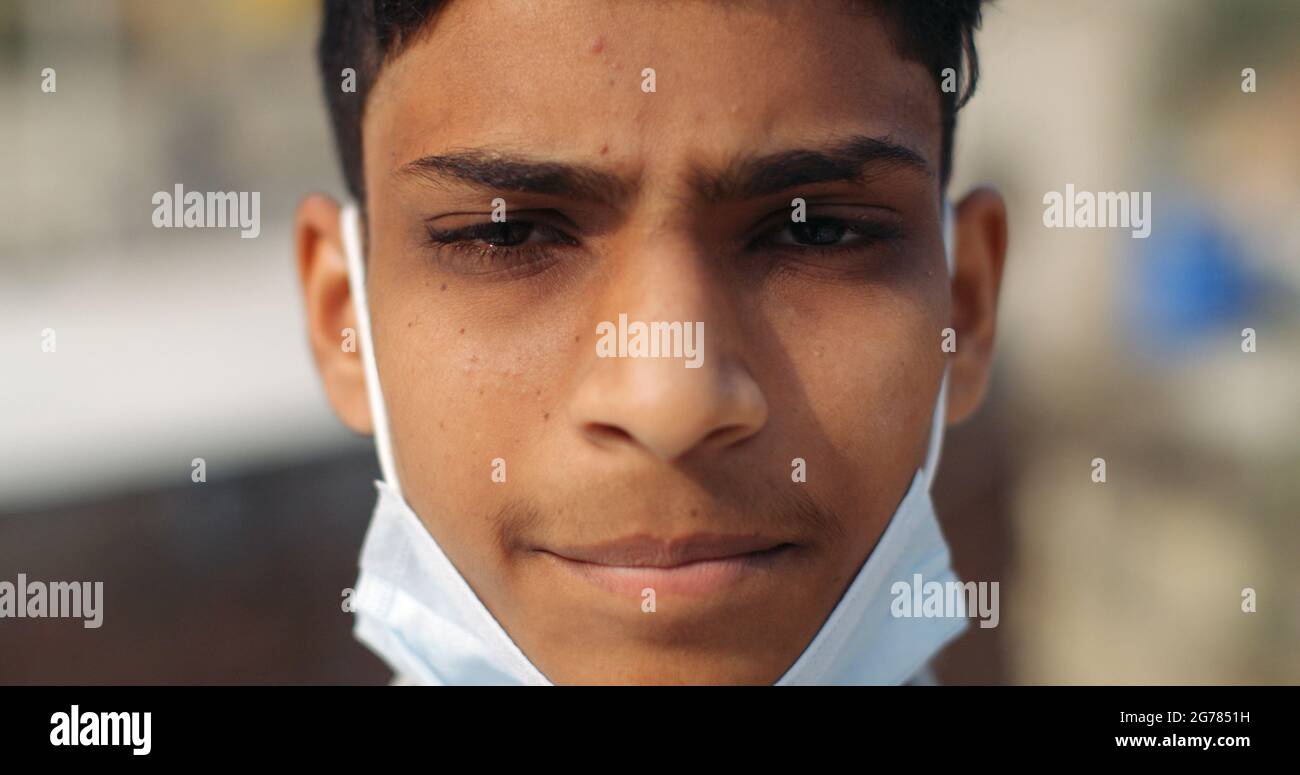 Nahaufnahme eines indischen Jungen, der eine Maske unter dem Kinn trägt - neues normales Konzept Stockfoto