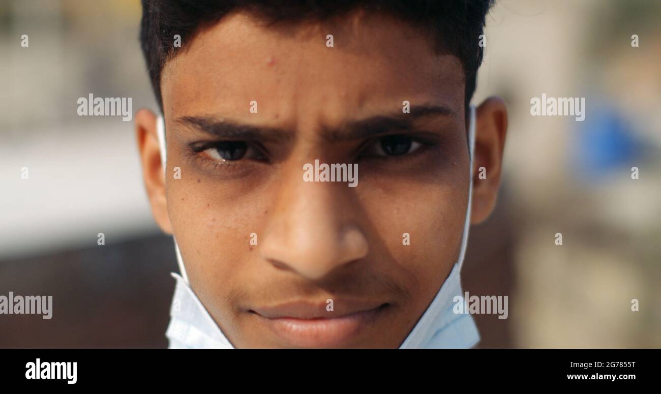 Nahaufnahme eines indischen Jungen, der eine Maske unter seinem Kinn trägt - neues normales Konzept Stockfoto