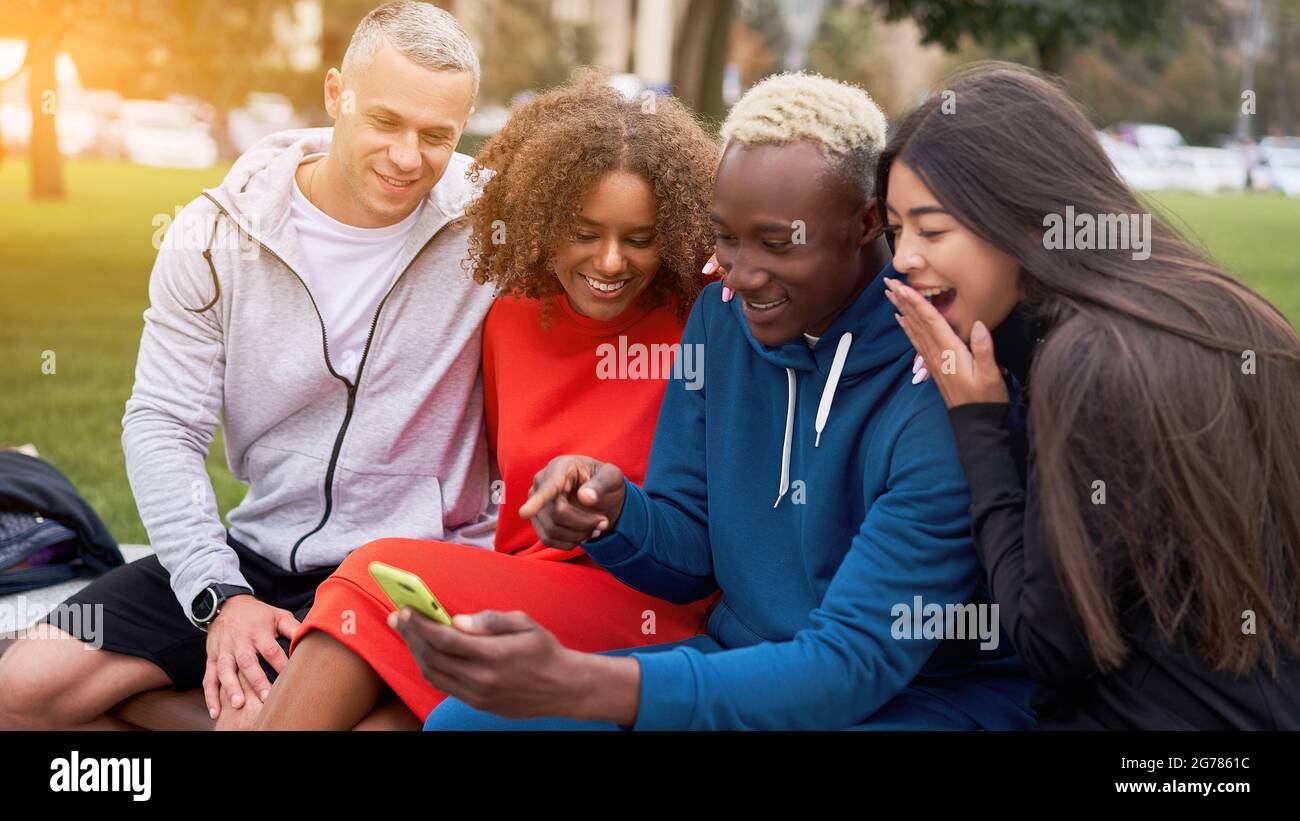 Multi ethnische Freunde im Freien suchen Smartphone-Bildschirm. Diverse Gruppe Menschen Afro american asiatisch kaukasisch verbringen Zeit zusammen multirassischen männlichen Fem Stockfoto