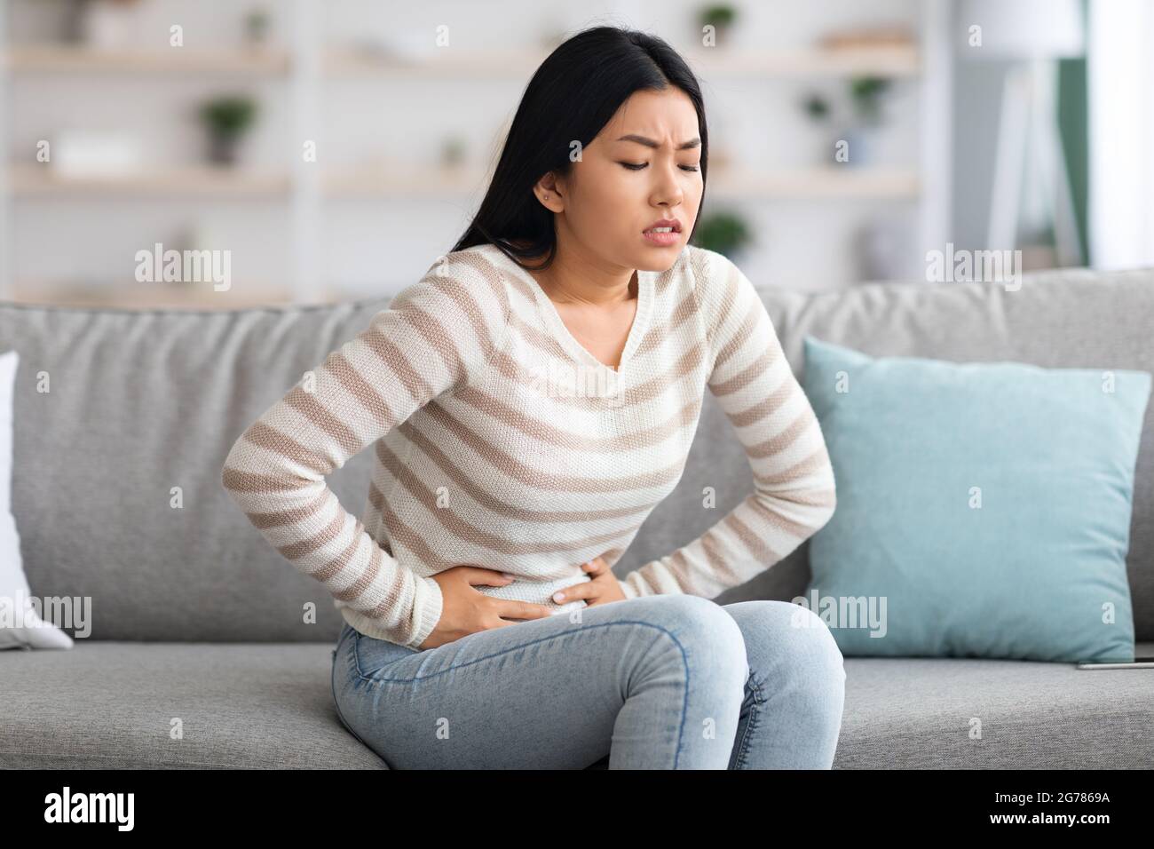 Magen-Ache. Kranke Asiatische Frau, Die Zu Hause An Akuten Bauchschmerzen Leidet Stockfoto