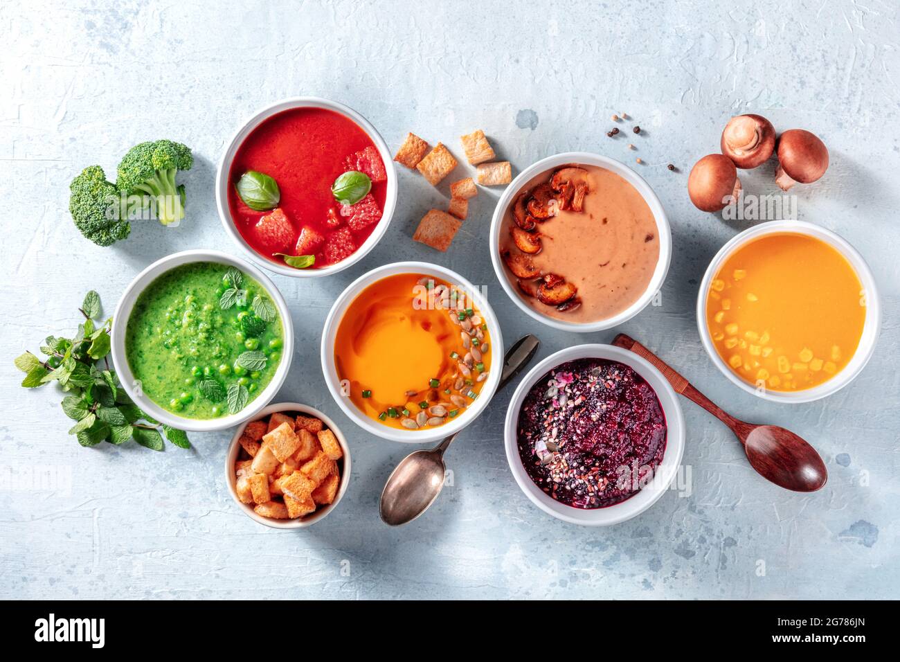 Vegane Suppenvielfalt, von oben geschossen. Grüne Erbse, kalte Tomaten, Kürbis, Pilzbete und süße Maissuppen mit Zutaten Stockfoto