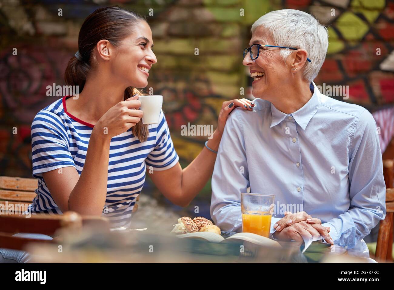 Ein junges Mädchen, das mit ihrer Großmutter in angenehmer Atmosphäre einen Kaffee in der Bar genießt. Freizeit, Bar, Freundschaft, Outdoor Stockfoto