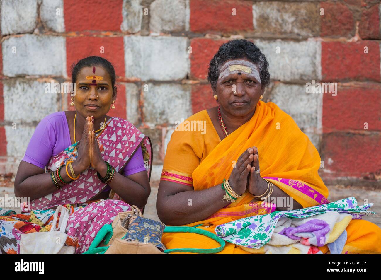 Zwei indische hindu-Weibchen, die in Gebetshaltung mit gekreuzten Beinen sitzen (Lotusposition), lächeln für ein Foto, Kanyakumari, Tamil Nadu, Indien Stockfoto