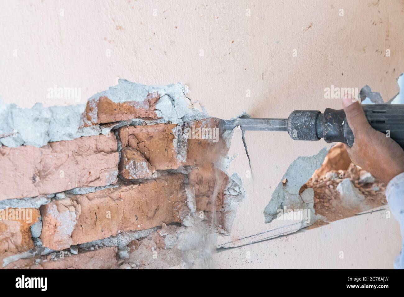 Arbeiter verwenden Abbruchhammer Bohrer, um die Wandoberfläche zu brechen. Bewegungsunschärfe beabsichtigt. Stockfoto