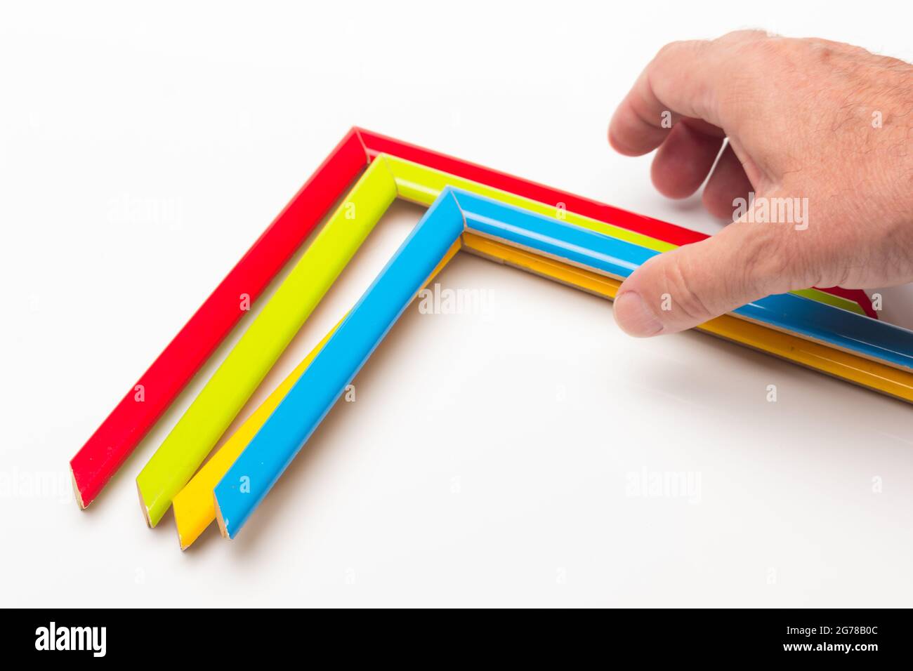 Hand, Finger und verschiedene Farben; Buntstifte, voller Bereich; farbige Winkel, die von der Hand eines Erwachsenen gehalten werden Stockfoto