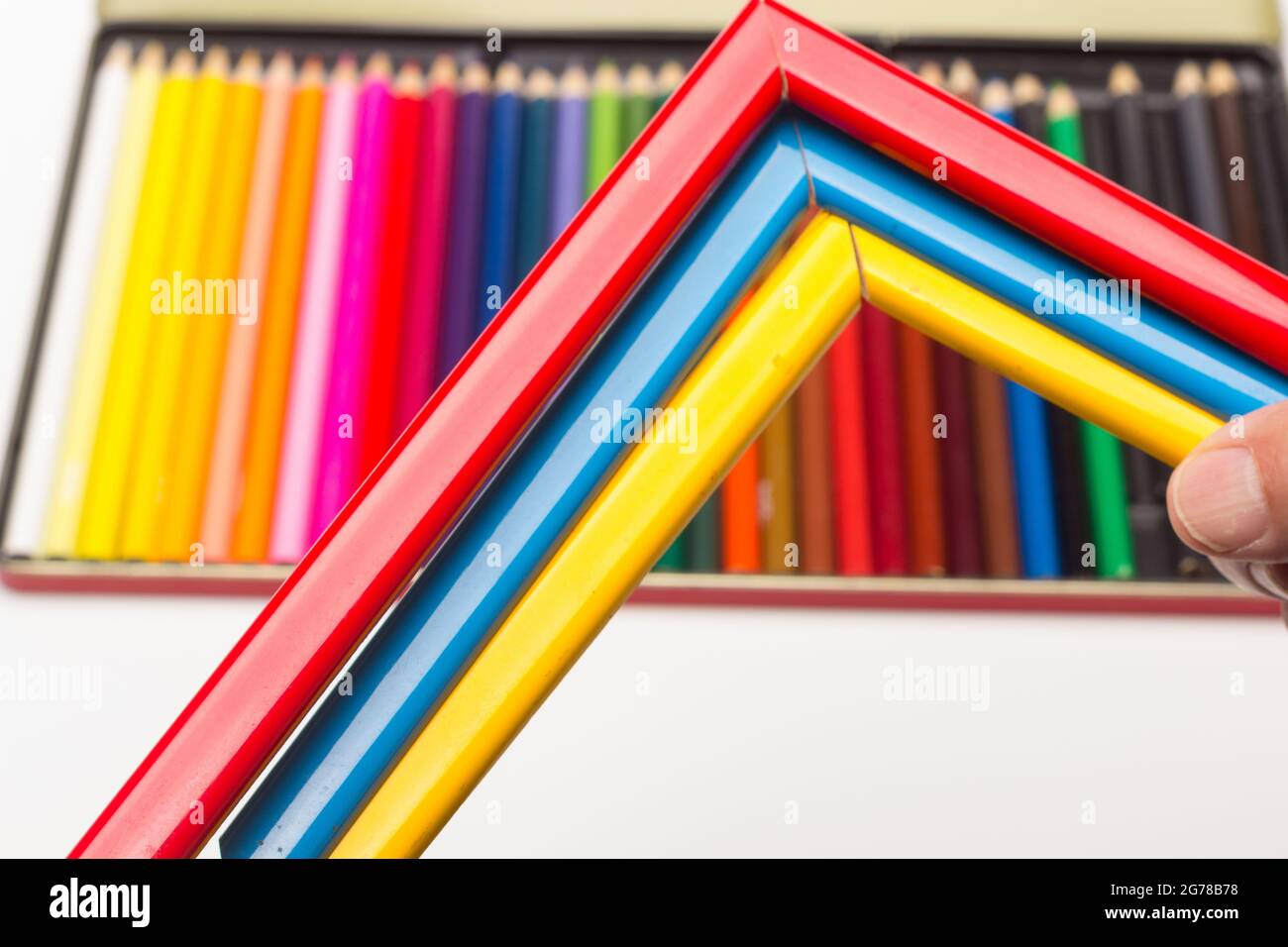 Hand, Finger und verschiedene Farben; Buntstifte, voller Bereich; farbige Winkel, die von der Hand eines Erwachsenen gehalten werden Stockfoto