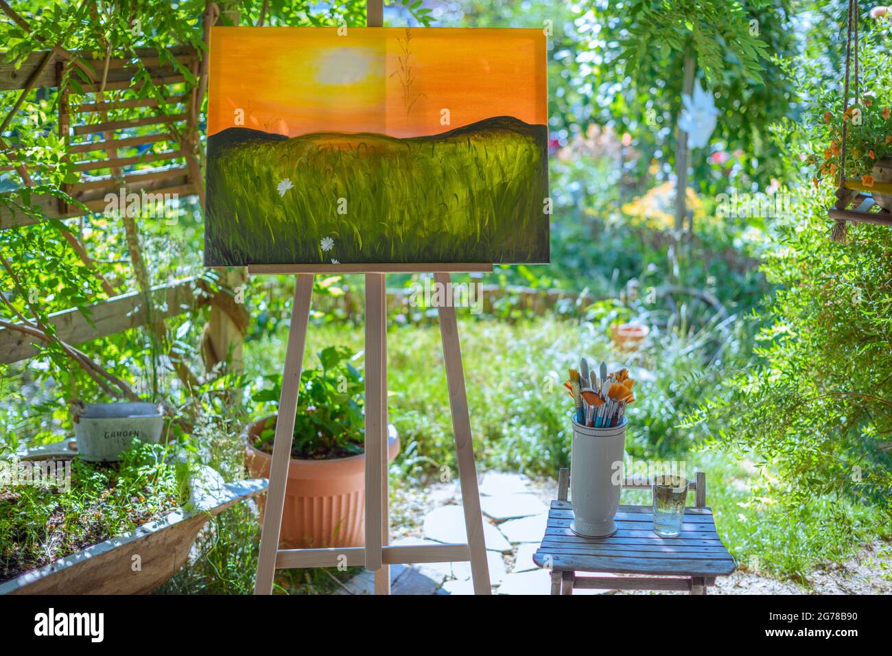 Staffelei mit Leinwandmalerei im Freien in einem Garten. Achtsamkeit, Kunsttherapie und kreatives Hobbys Konzept. Stockfoto
