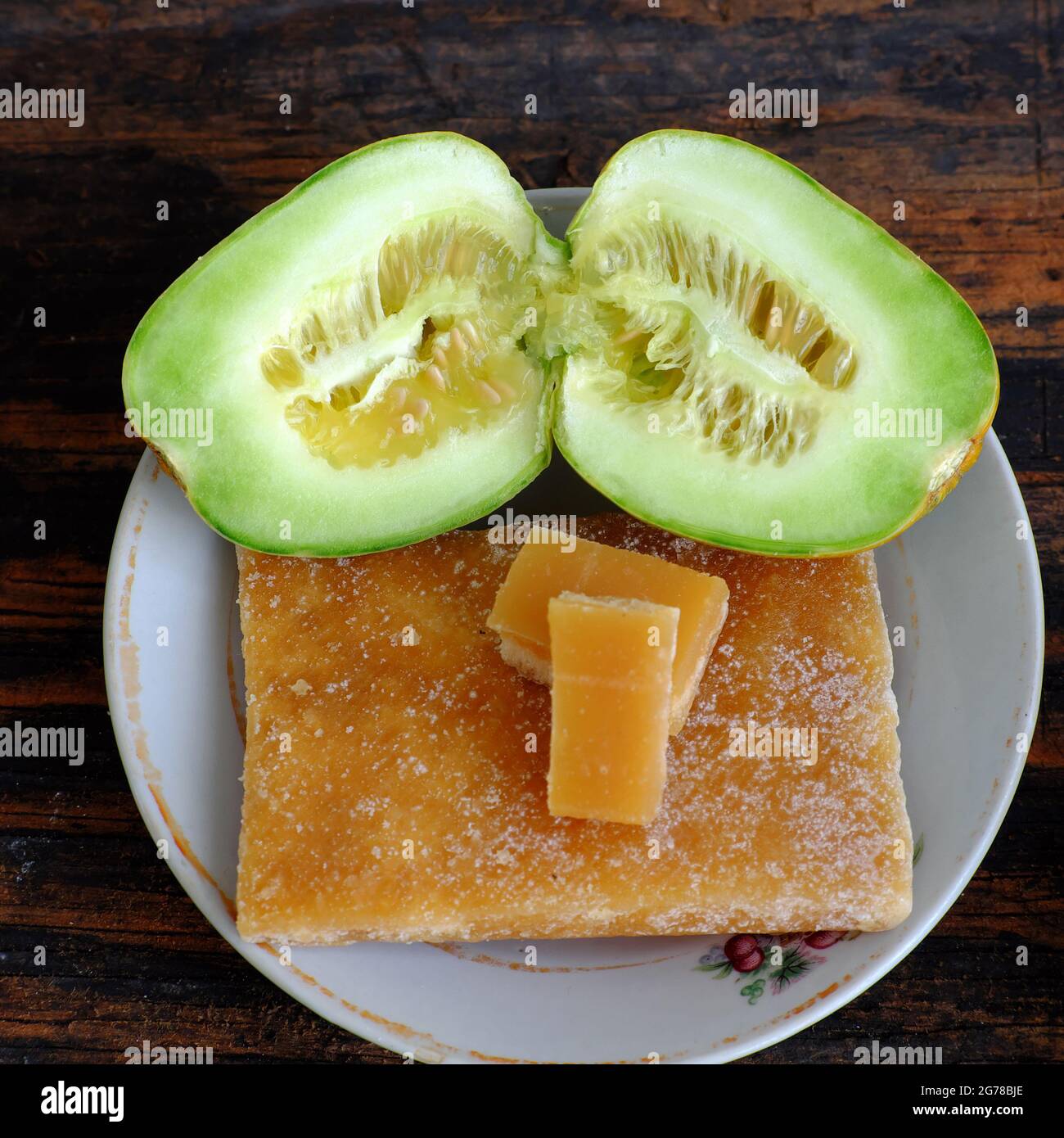 Melonenfrüchte, halbiert, bereit, mit dem Zuckerrohr auf hölzernem Hintergrund zu essen, wachsen kleine landwirtschaftliche Produkte auf der Terrasse des Stadthauses Stockfoto