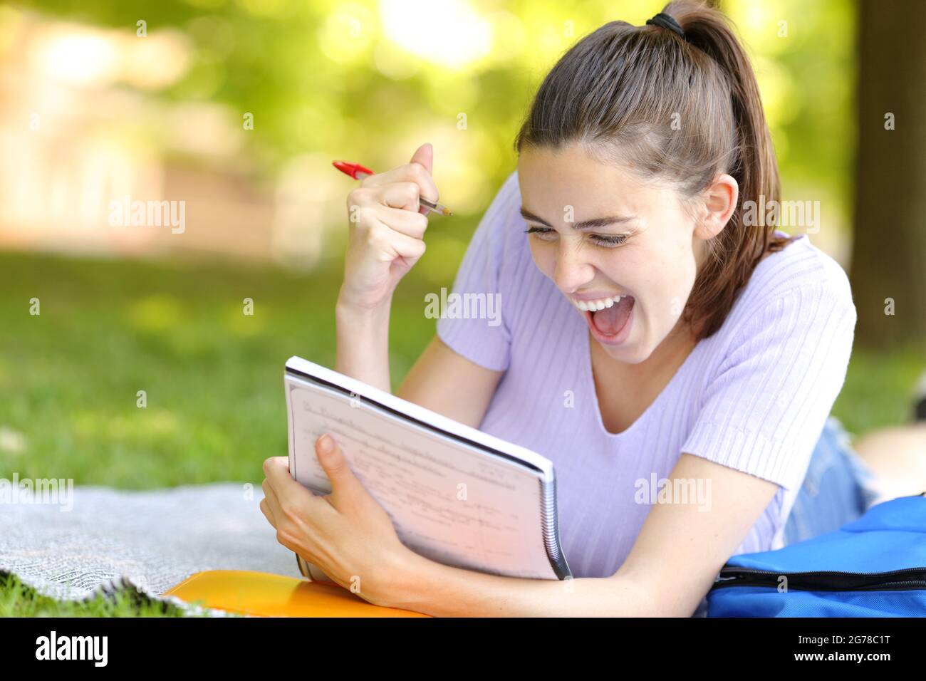 Begeisterter Student feiert Erfolg beim Lesen von Notizen auf einem Campus Stockfoto