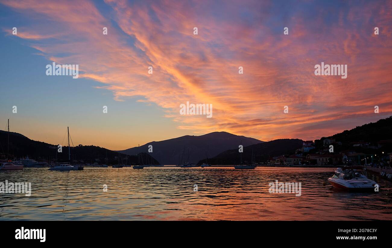 Ionische Inseln, Ithaka, Bucht von Molos, Vathi, Dämmerung, Blick von Vathi auf die Bucht, Segelboote, rosa beleuchtete Schleierwolken über der Bucht, blauer Himmel, dunkles Meer Stockfoto