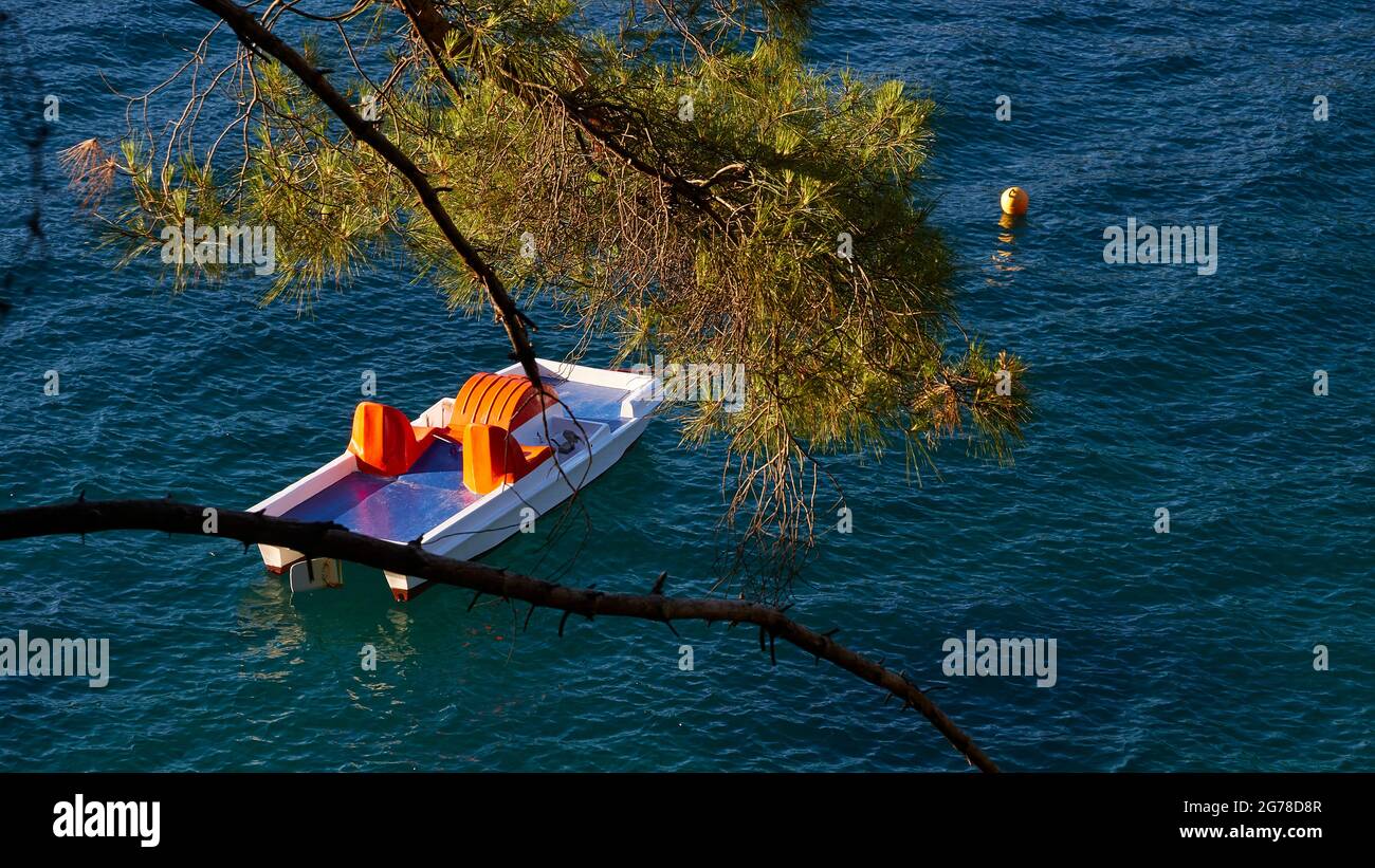 Ionische Inseln, Ithaca, Insel Odysseus, Vathi, Loutsa Beach, Grünes Wasser, blaues Wasser, Bäume am Strand, einsamer Strand, Tretboot vor Anker, Blick durch Bäume Stockfoto