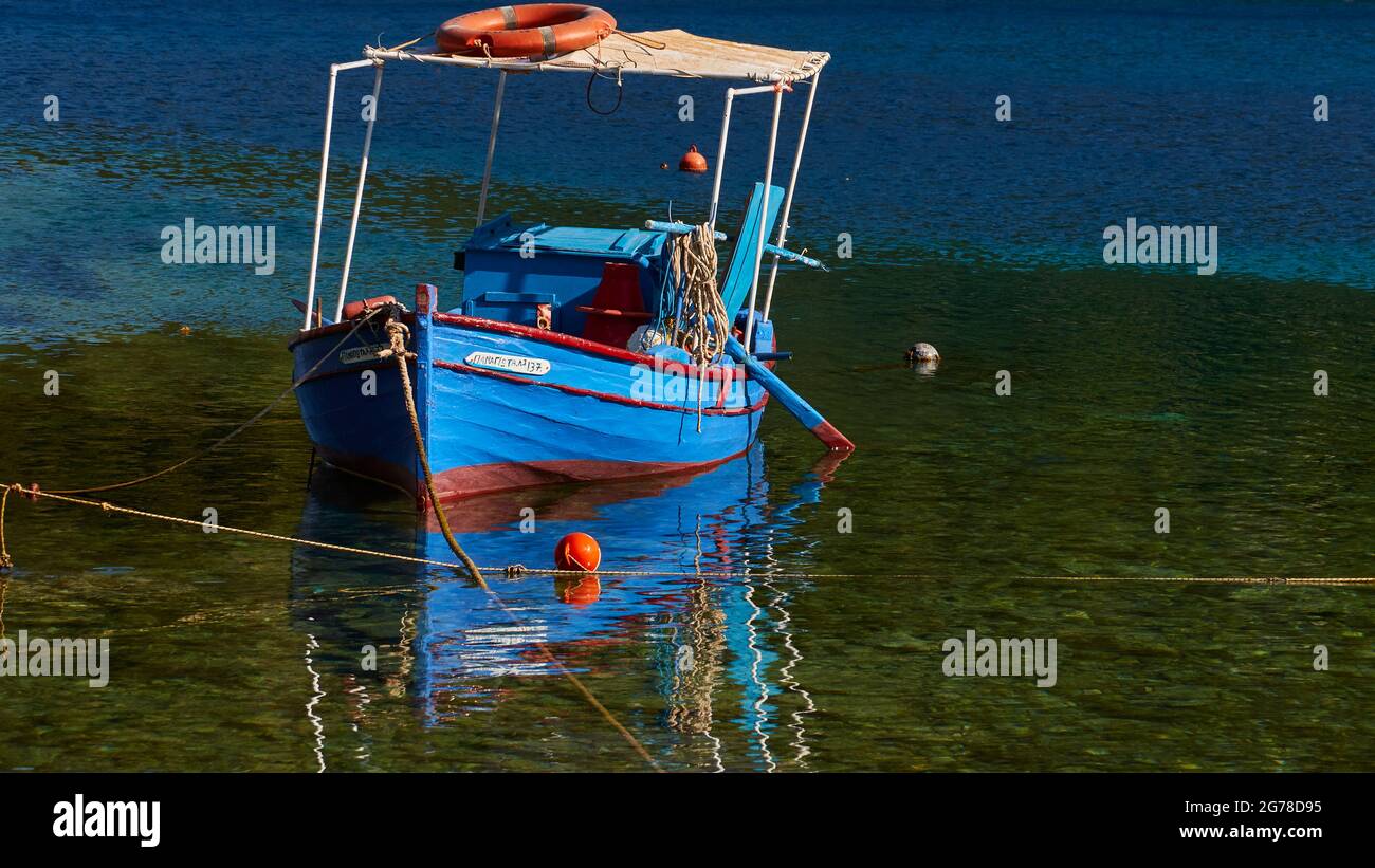 Ionische Inseln, Ithaca, Insel Odysseus, in der Nähe von Vathi, Sarakiniko Beach, Boote, Segelboote, blaues, grünes und türkisfarbenes Wasser, Traumbucht, blauer Himmel, einzelnes blau-rotes Fischerboot, Spiegelung auf dem Wasser Stockfoto