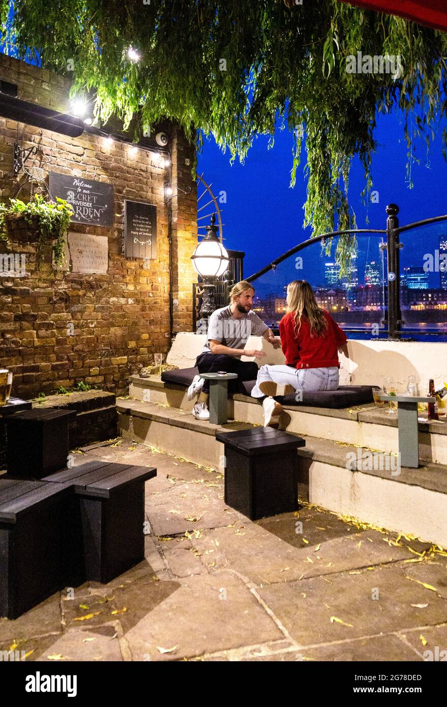 Ehepaar sitzt im Garten des alten historischen Prospect of Whitby Pub in Wapping mit Blick auf die Themse, London, Großbritannien Stockfoto