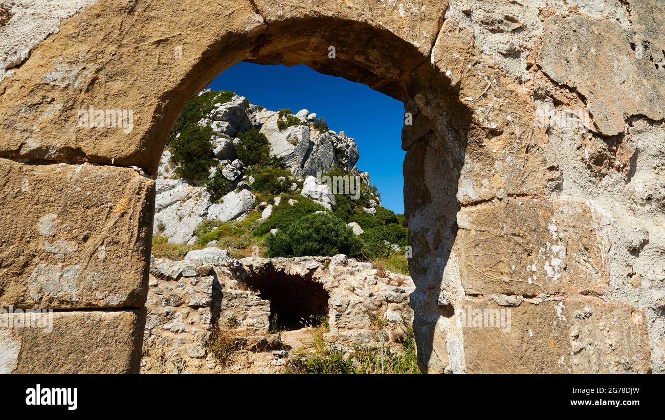 Ionische Inseln, Zakynthos, Berg in der Nähe von Zakynthos Stadt, Monte Yves, Kloster auf dem Gipfel, Panagia Skopiotissa, 15. Jahrhundert n. Chr., steht auf den Ruinen eines antiken Artemis-Tempels, dunkelblauer Himmel, Blick durch den Bogen einer Steinmauer zu anderen Gebäuden und felsigen Hügel Stockfoto