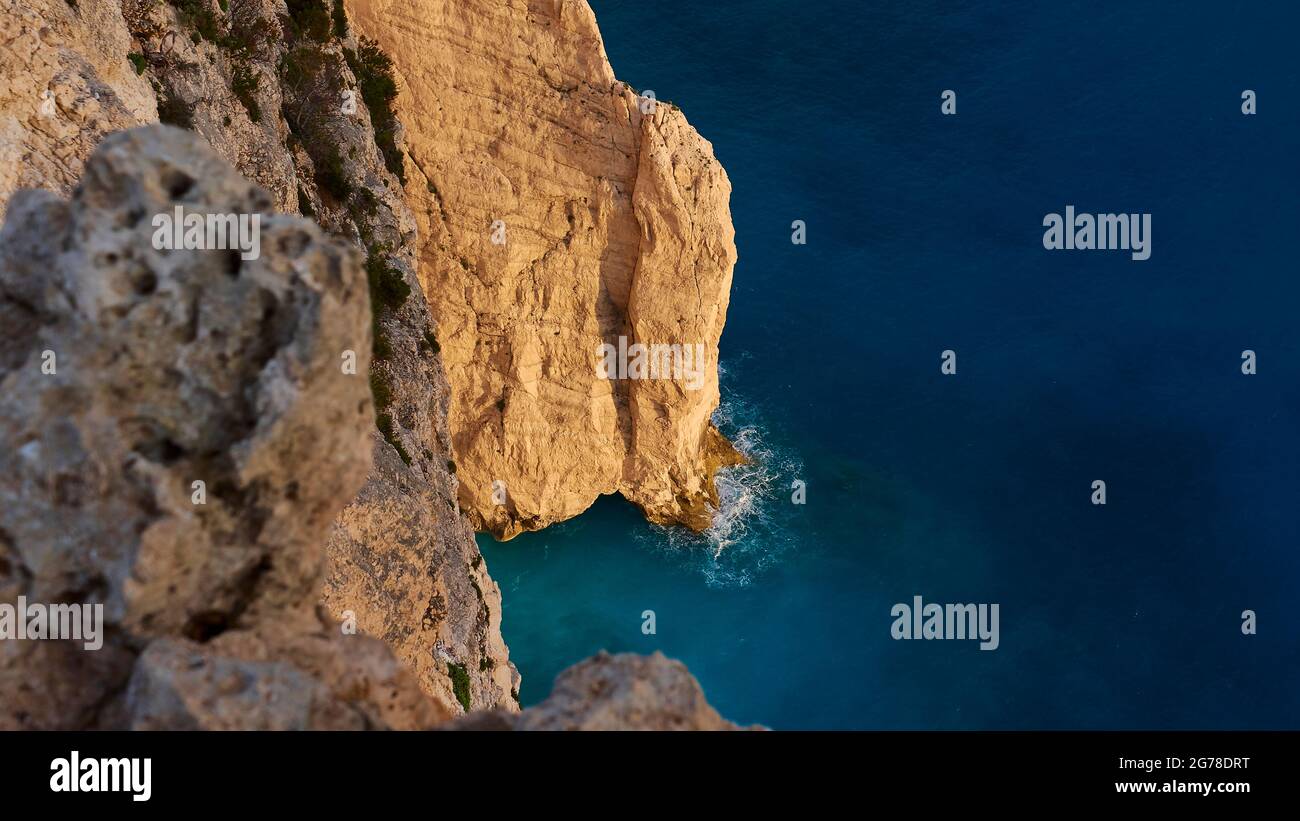 Zakynthos, Paralia Navagio, Shipwreck Beach, Blick von oben auf Felsen im Abendlicht, Felsen im Schatten links, blaues und türkisfarbenes Wasser, kein Himmel Stockfoto