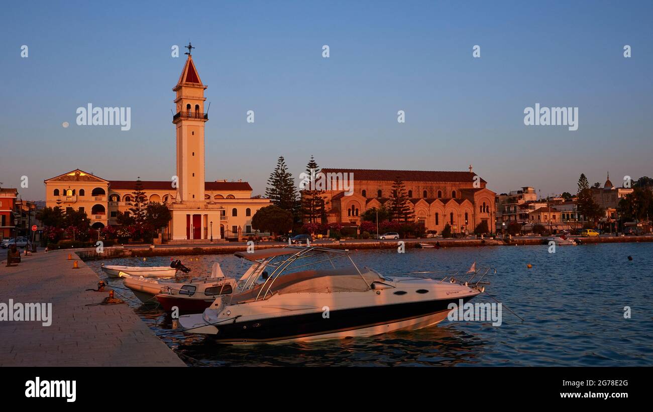 Zakynthos Stadt, Morgenlicht, Kirche St. Dionisios, Boote im Hafen im Vordergrund, blauer Himmel, Mond neben Kirchturm Stockfoto