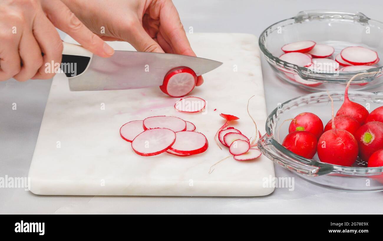 Frisch geschnittenes Rettich Nahaufnahme auf Marmor Schneidebrett auf hellgrauem Hintergrund. Gemüsesalat Zubereitungsverfahren, Rezept Stockfoto