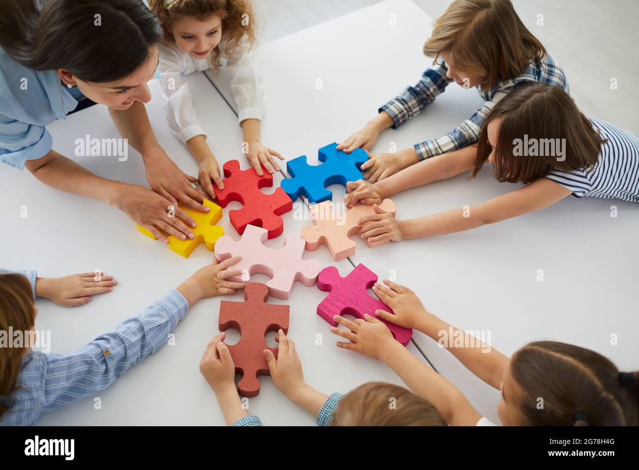 Team von kreativen kleinen Kindern mit Lehrer zusammen Puzzleteile Stockfoto