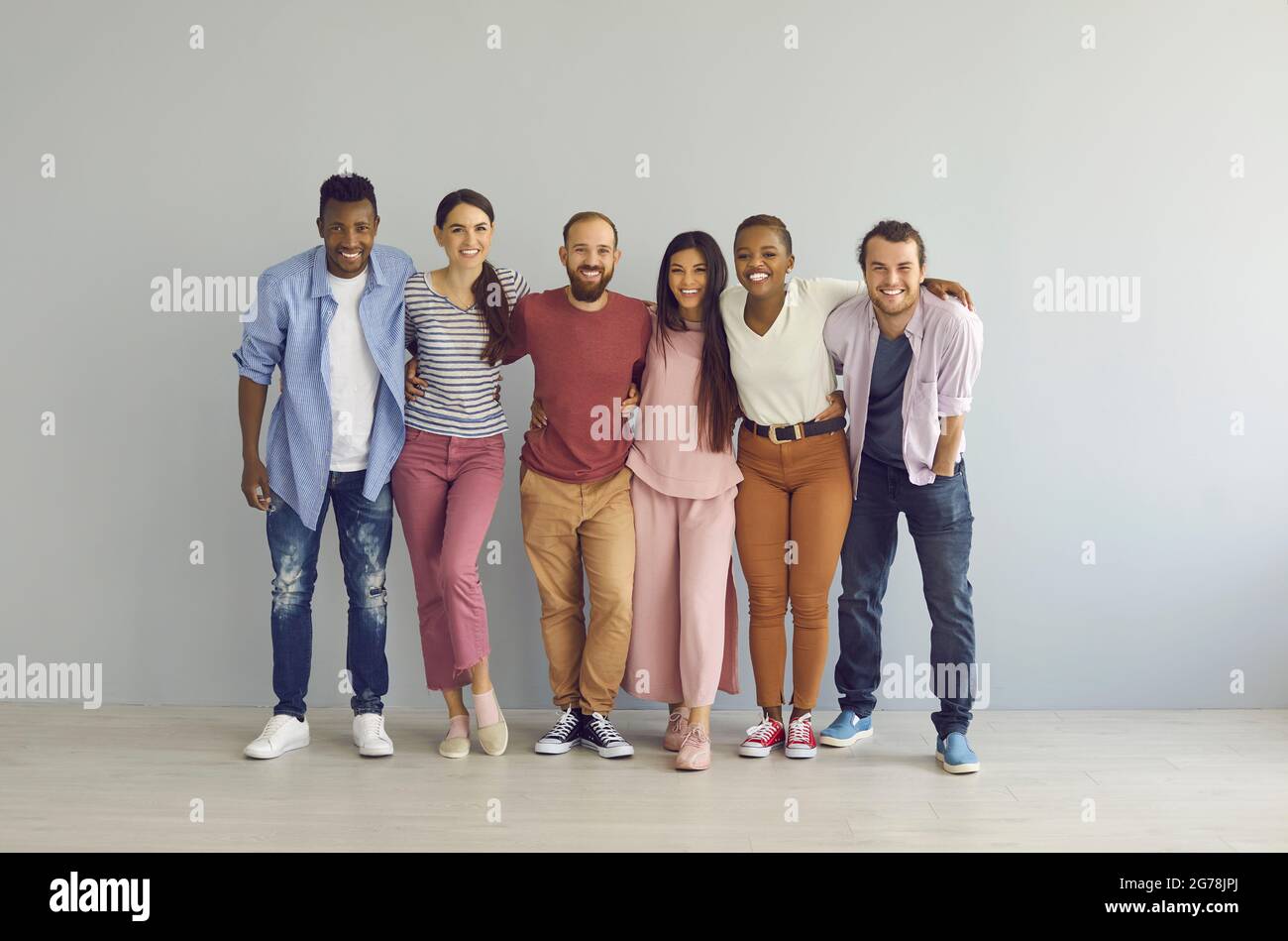 Porträt glücklicher multirassischer Freunde, die vor dem Hintergrund einer hellen Wand umarmt stehen. Stockfoto
