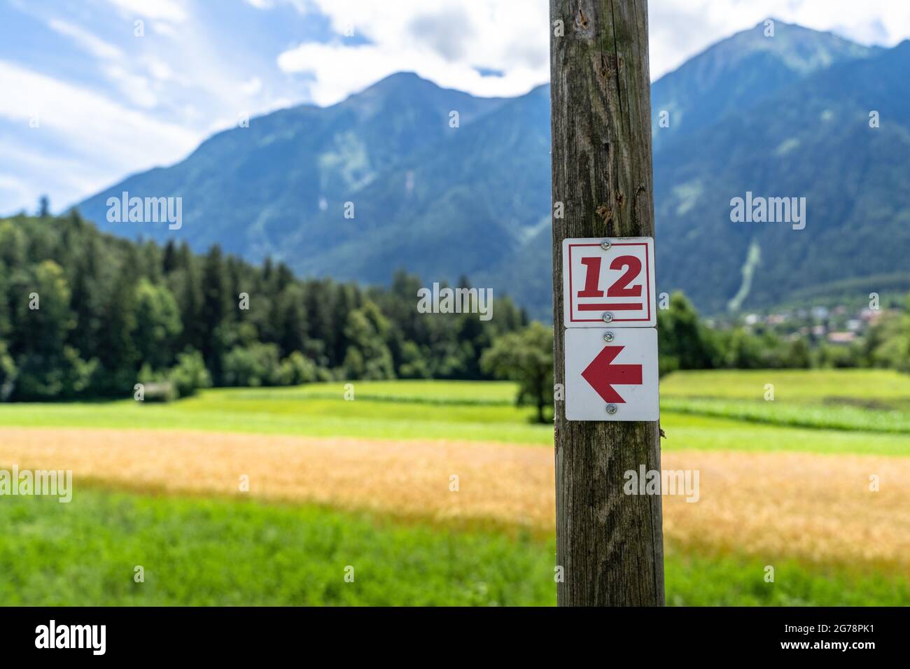Europa, Österreich, Tirol, Ötztal Alpen, Ötztal, Ambach, Wegweiser des Ötztaler Urweg auf einem Holzpfahl vor einem Feld Stockfoto