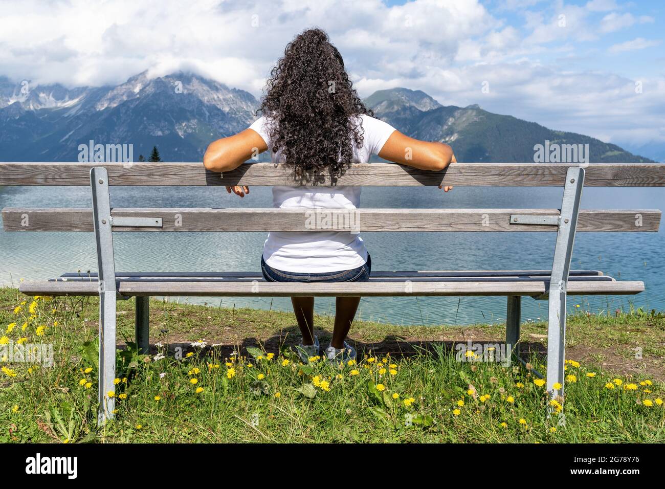 Europa, Österreich, Tirol, Stubaier Alpen, Urlauber sitzt auf einer Bank und blickt über einen Stausee auf die Stubaier Berge Stockfoto