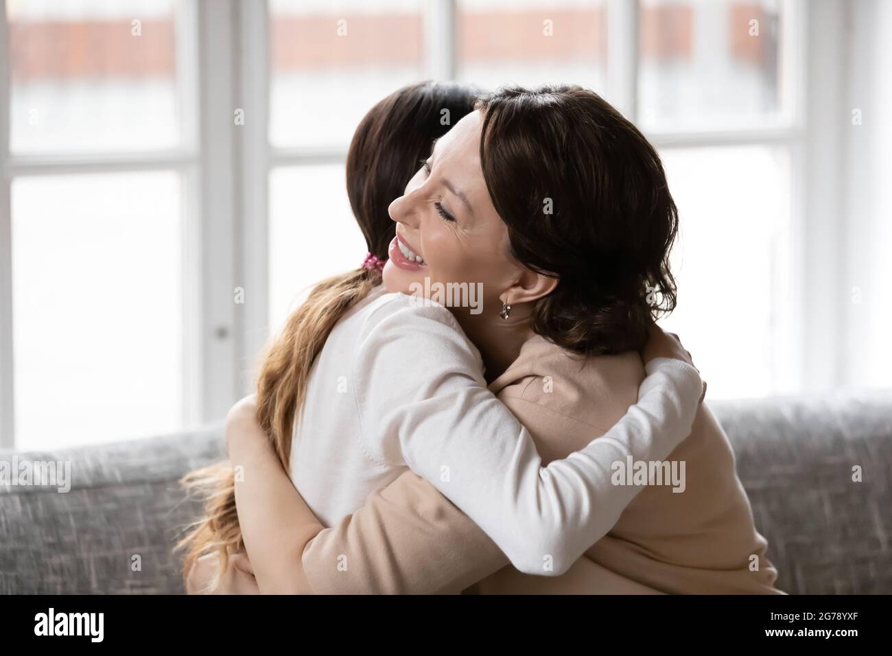Glückliche Erwachsene Tochter und alte Mutter umarmen zu Hause Stockfoto