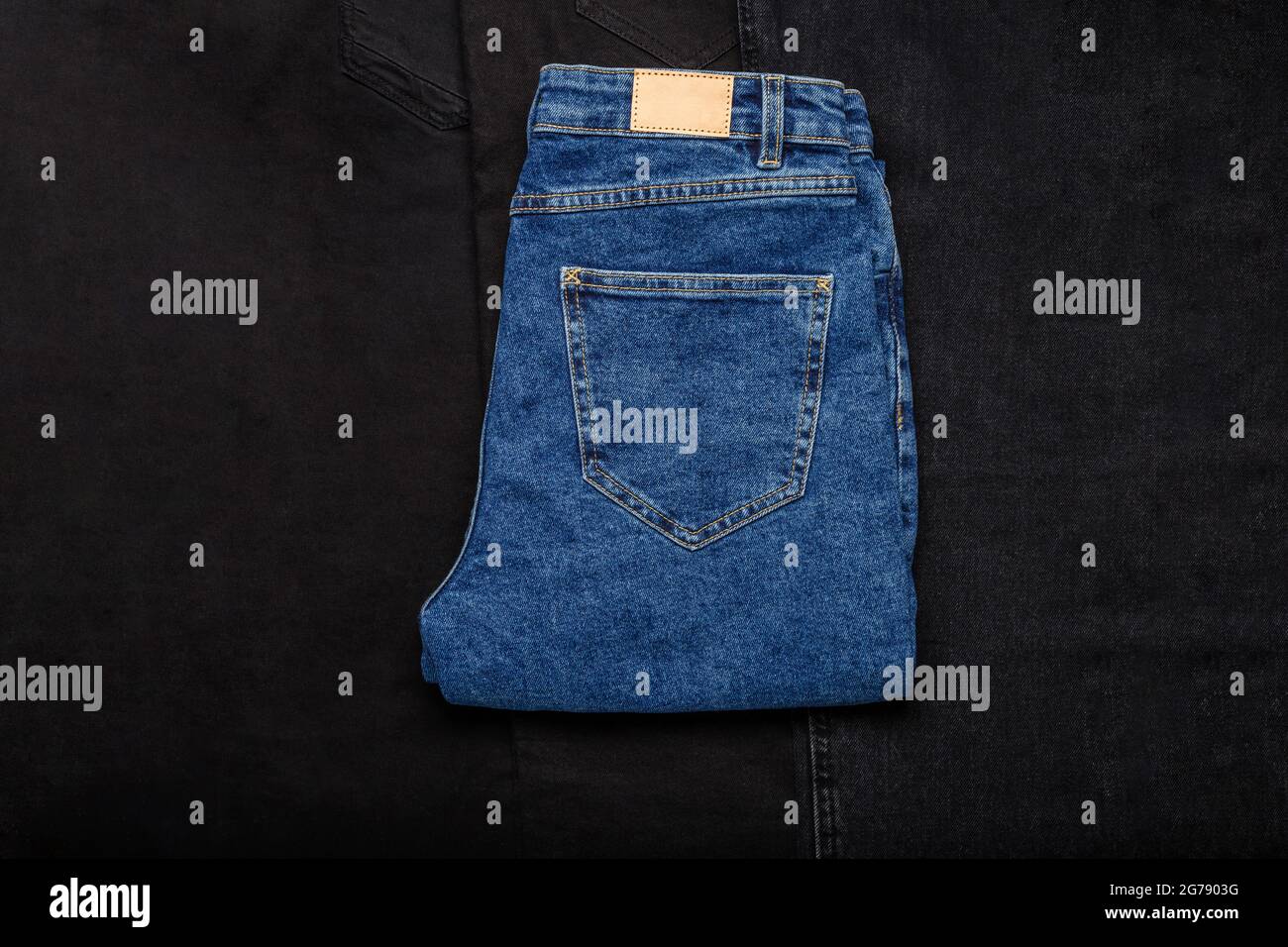 Blaue Jeans Denim Hose auf schwarzem Denim Jeans Textil Textur Stoff Hintergrund. Draufsicht. Stockfoto