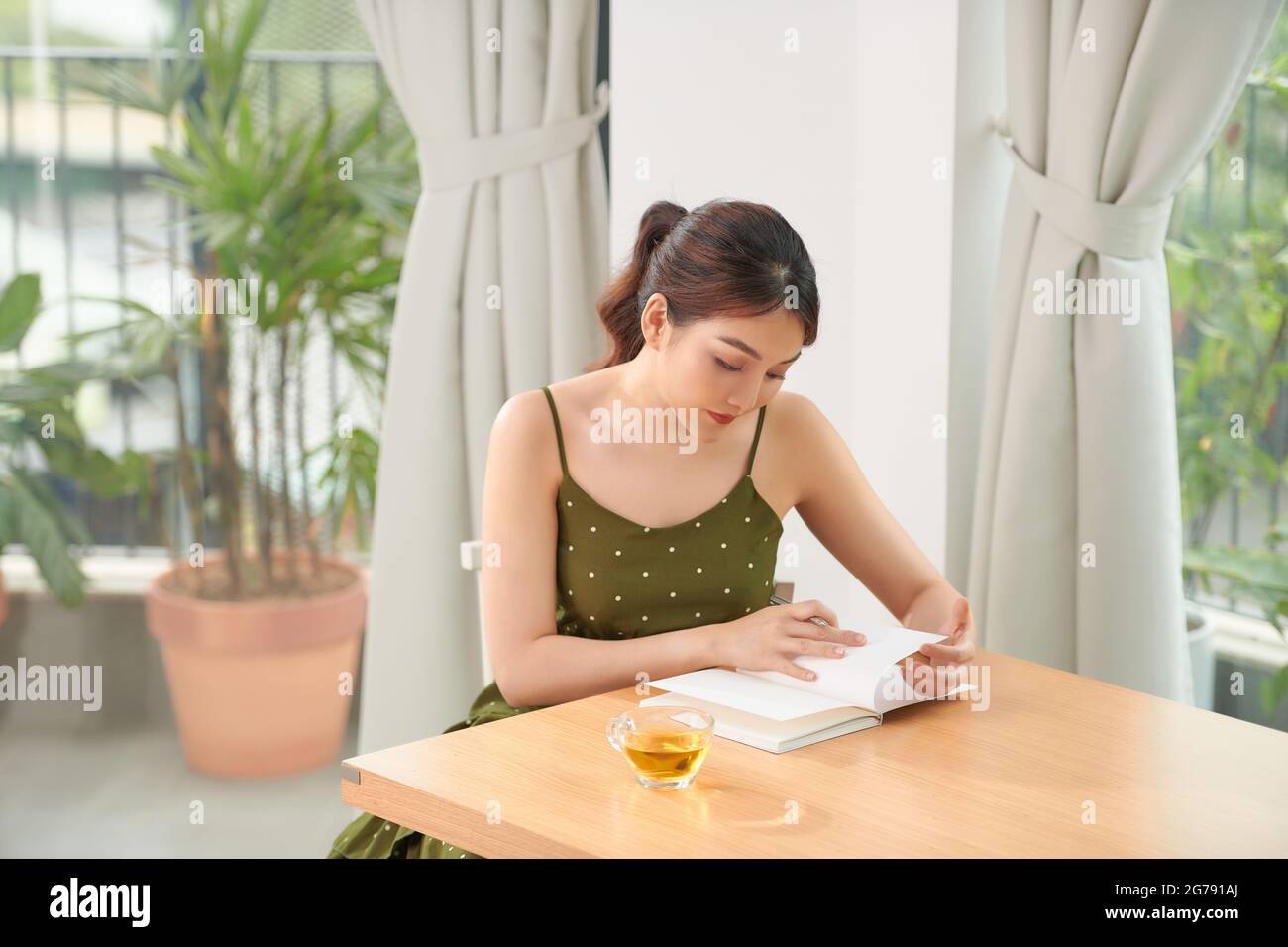 Schöne fröhliche junge Mädchen sitzt am Küchentisch, Notizen in einem Tagebuch Stockfoto