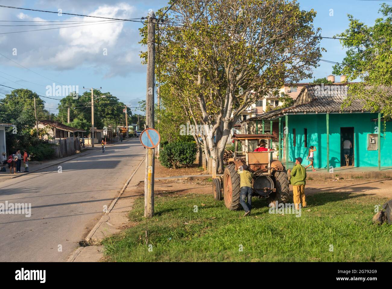 Kubanische Männer, die einen landwirtschaftlichen Traktor an einem Haus vorbeischieben, Holguin, Kuba, November 2016 Stockfoto