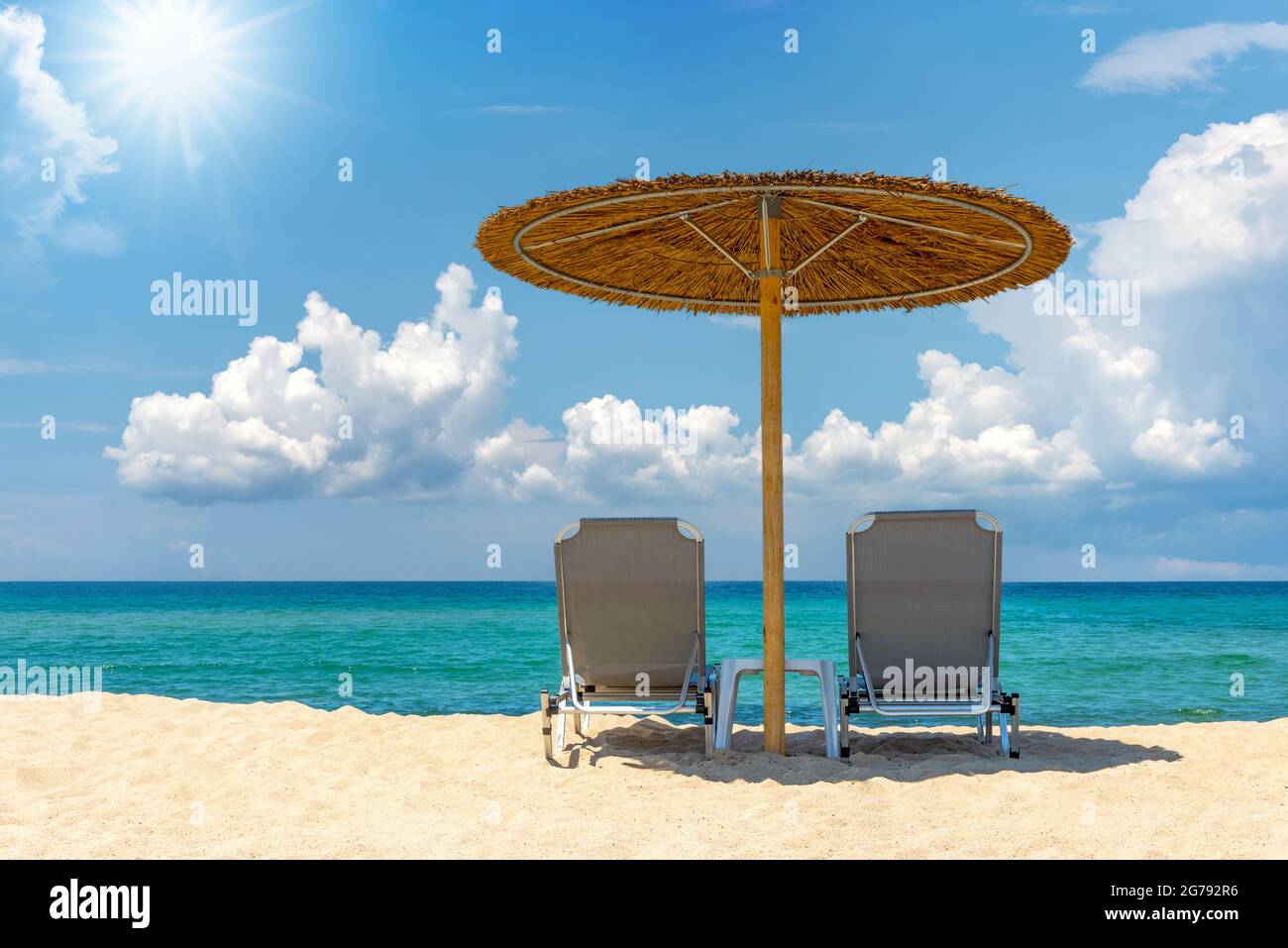 Liegestuhl mit Sonnenschirm mit blauem Himmel und Sonne am tropischen Strand Stockfoto