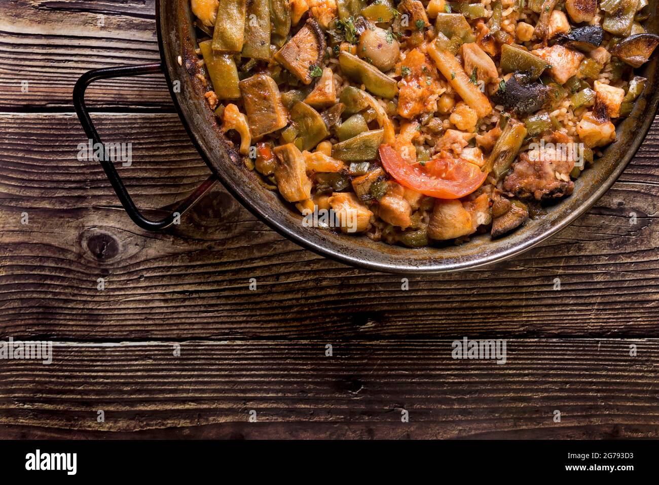 Traditionelle Paella auf einem Holztisch. Spanisches Essen, Essen zum Teilen mit der Familie Stockfoto