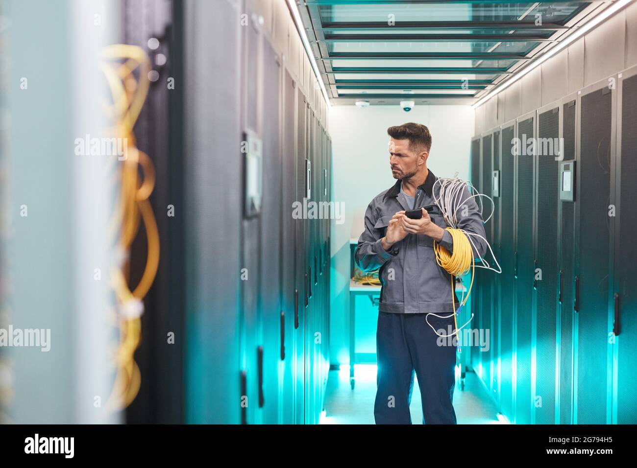 Porträt eines bärtigen Netzwerktechnikers, der den Serverraum im Rechenzentrum inspiziert und den Platz für Kopien untersucht Stockfoto